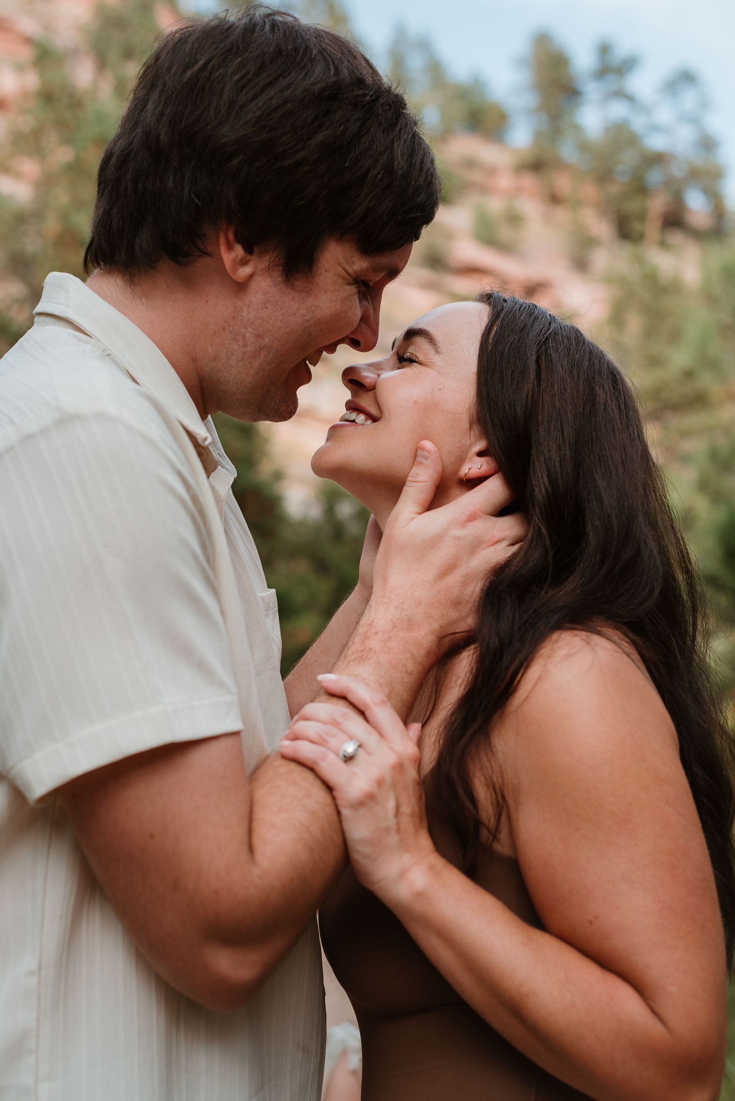 A romantic couple sharing an intimate kiss outdoors with natural desert scenery in the background.