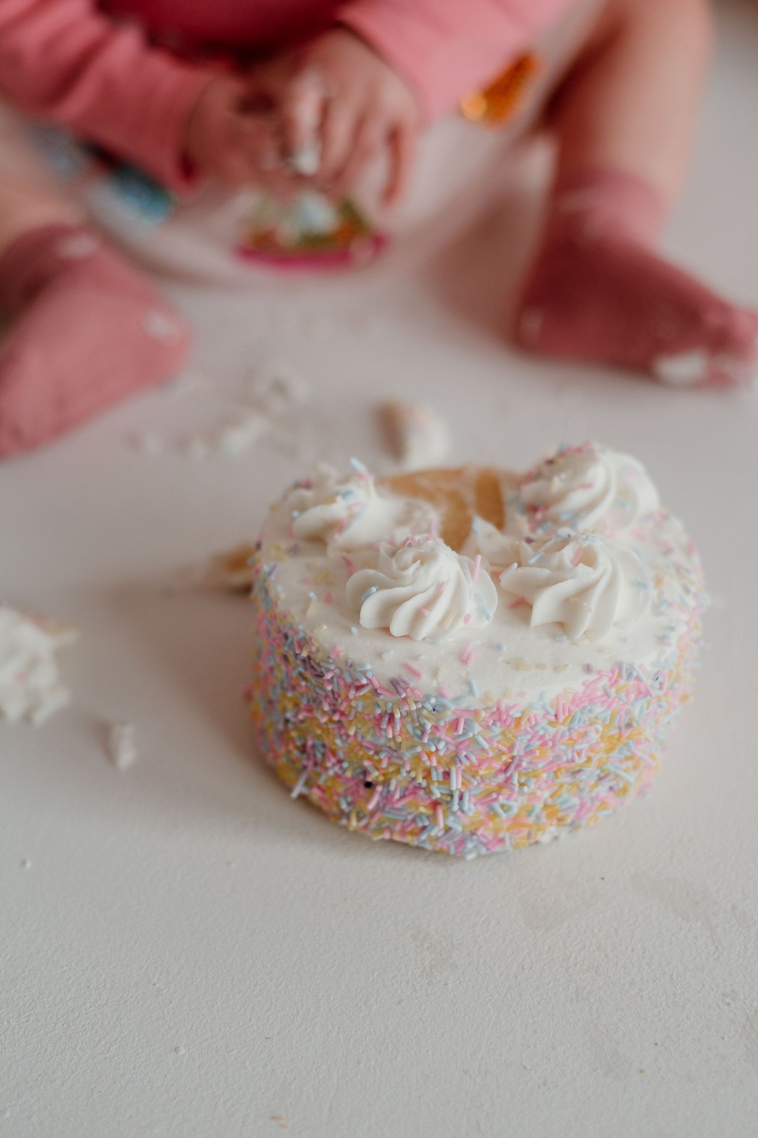 Close-up sequence of a frosted donut with colorful sprinkles on white surface.