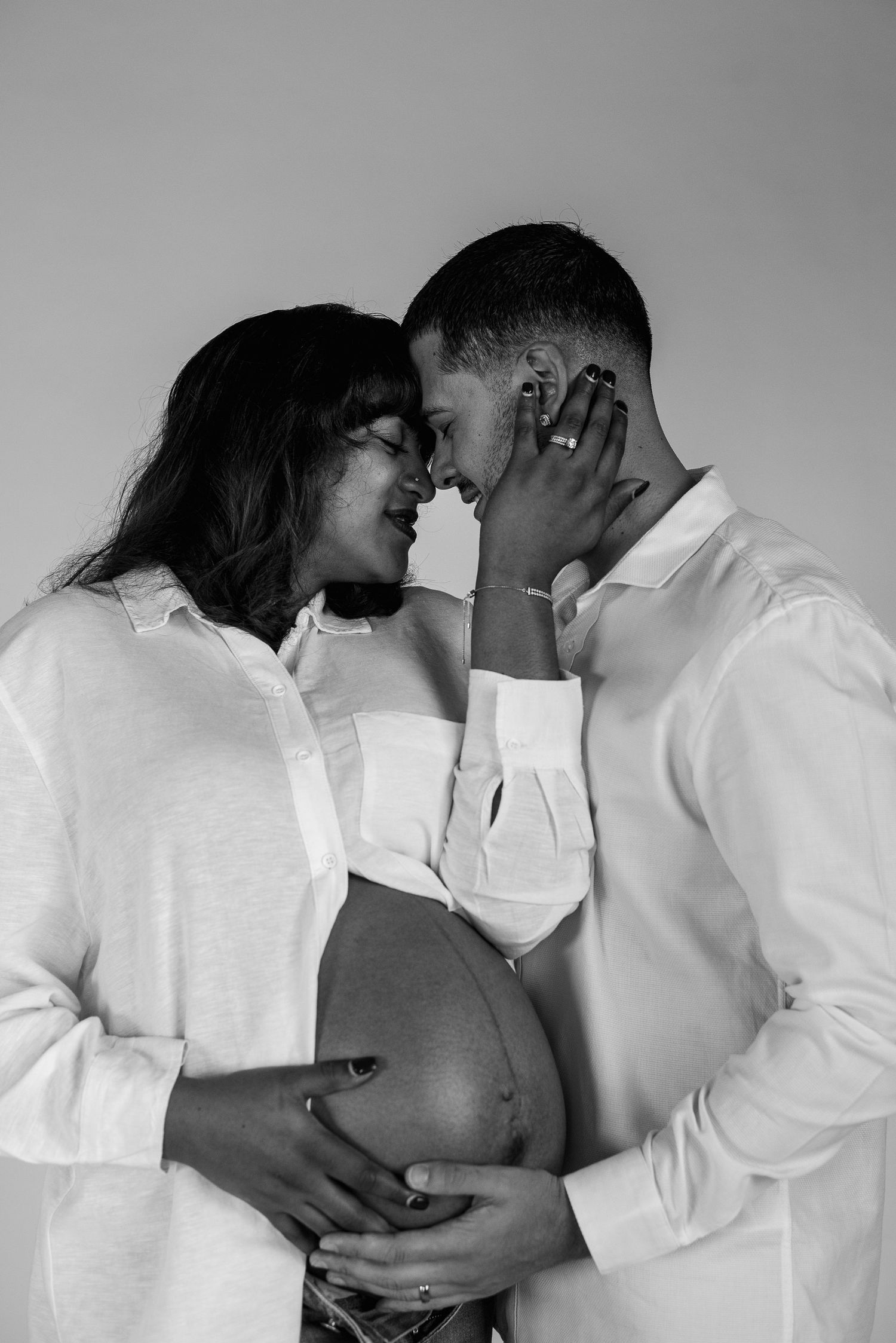 Intimate black and white maternity portrait showing tender moment between expectant couple.