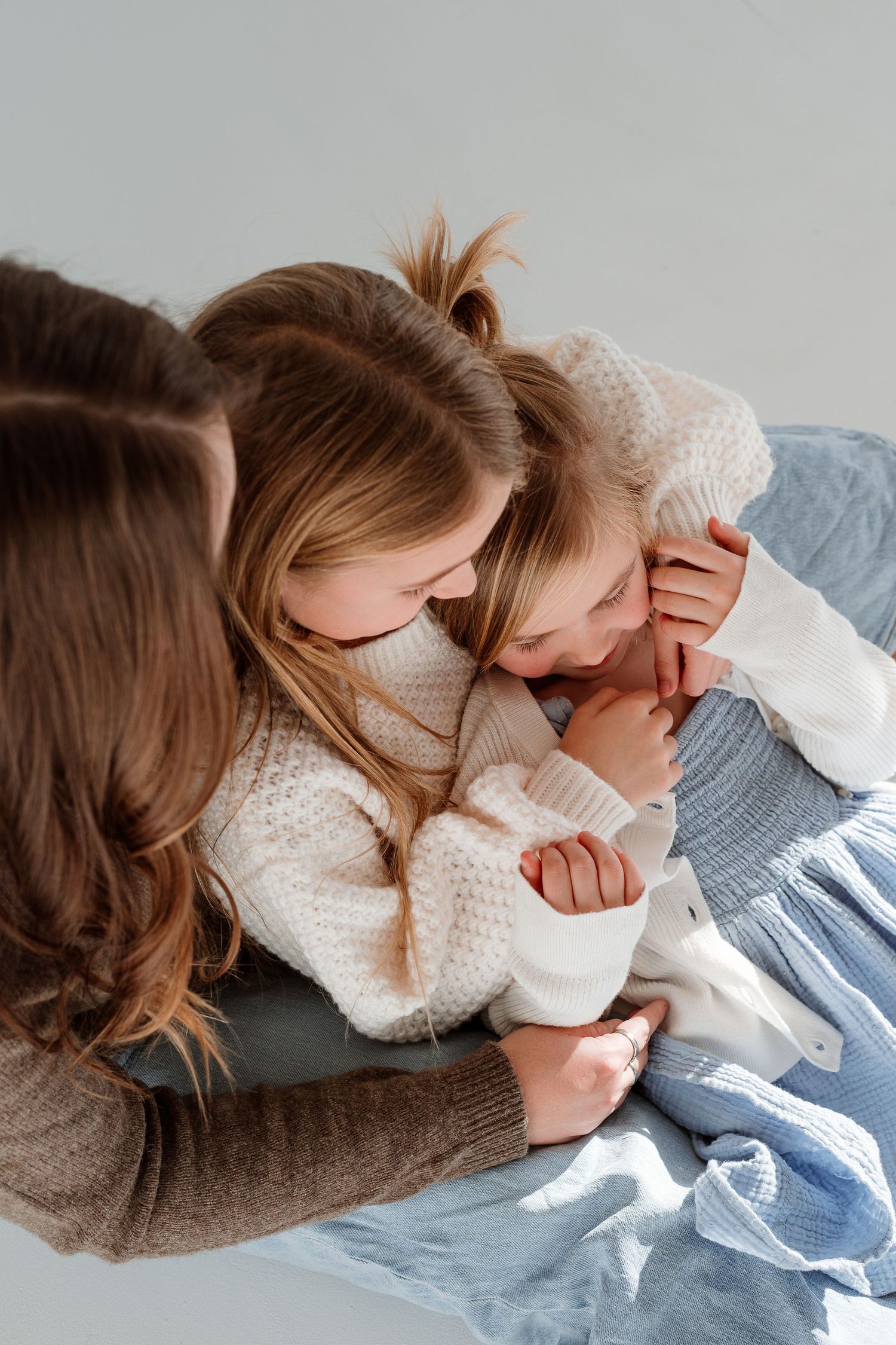 A series of tender moments captured in white and grey tones showing a loving embrace on a couch.