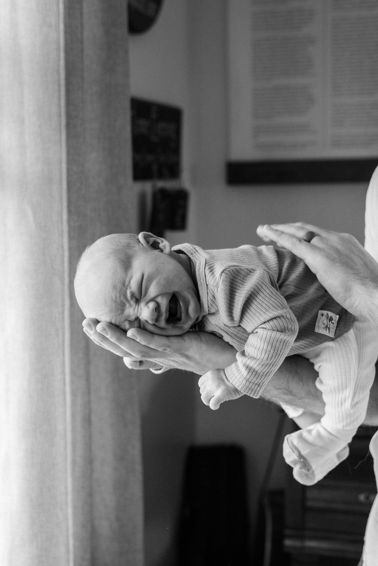 Series of black and white images showing a baby being held horizontally in gentle hands.