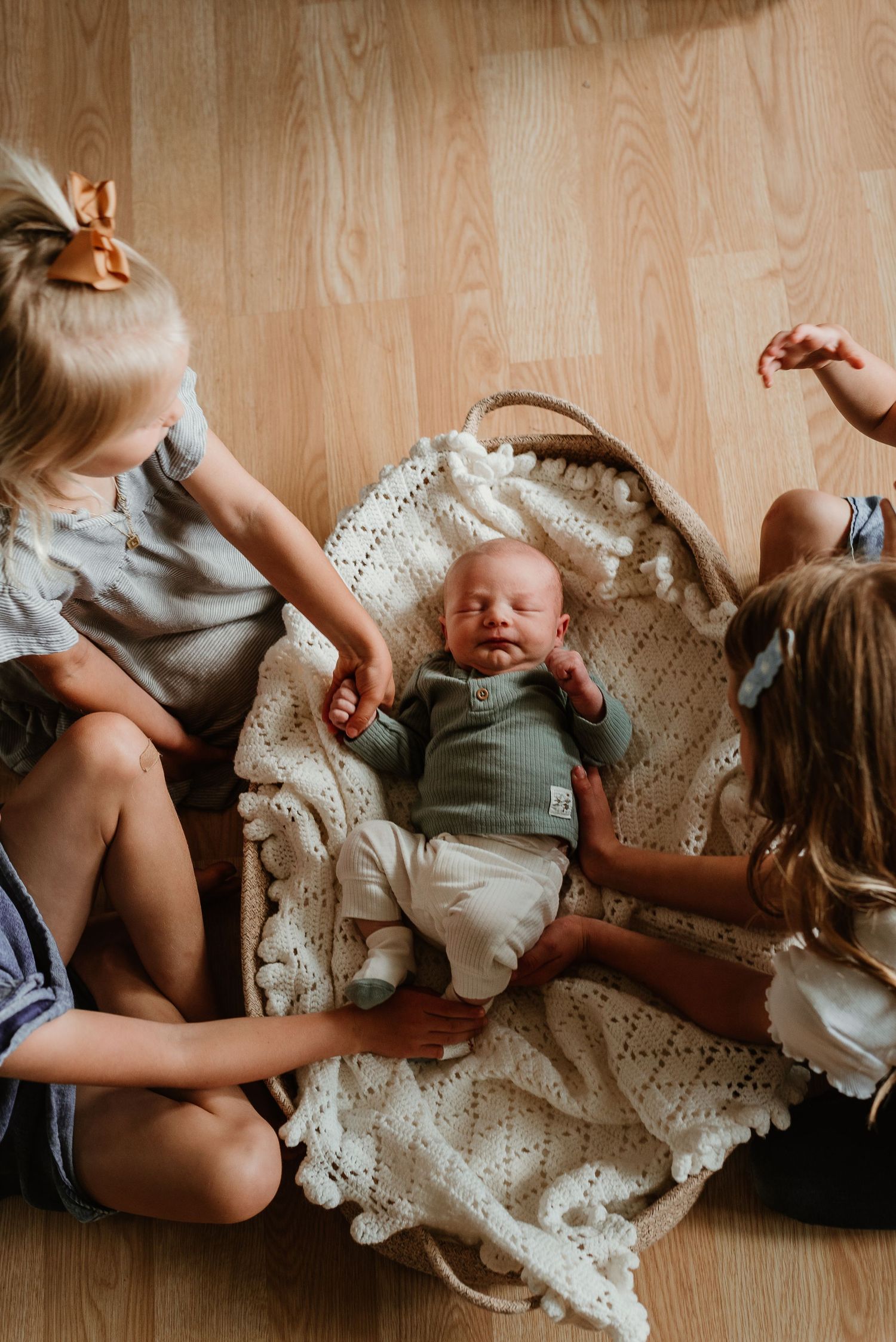 Baby lying on crocheted blanket with family members in casual attire sharing intimate moments.