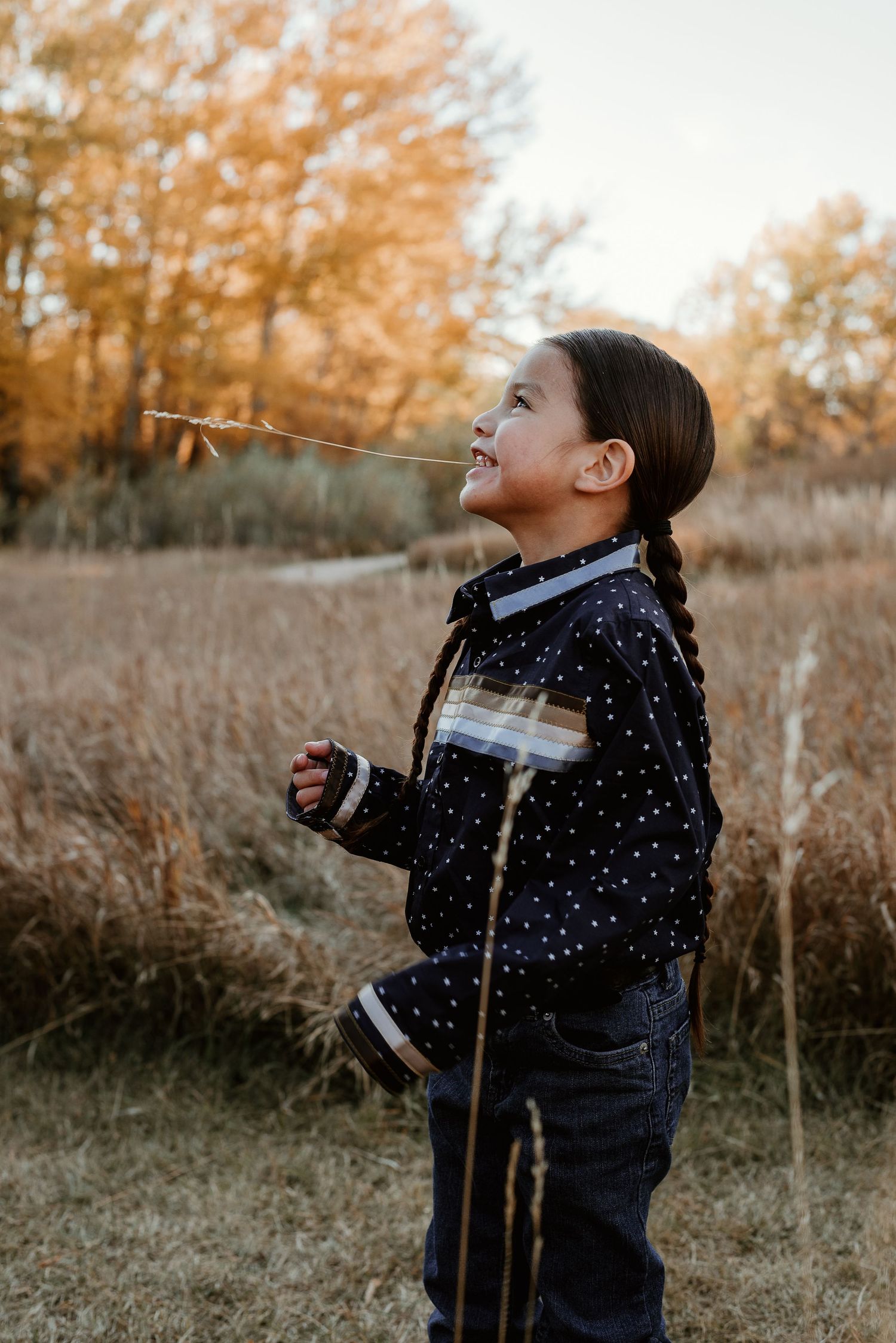 Person in navy polka dot jacket looking up with joyful expression in autumn field.