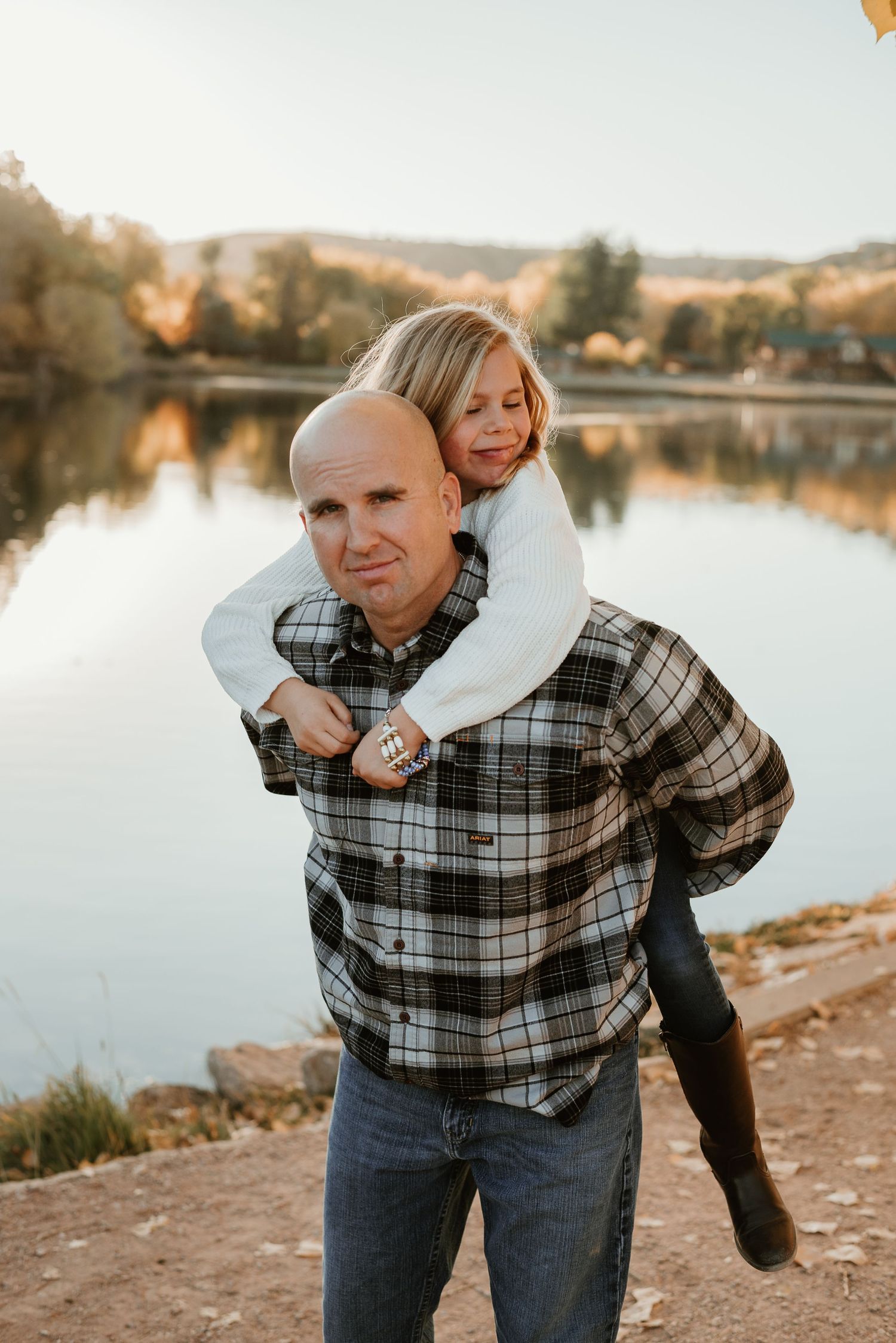 Sweet piggyback ride moment by the lake during golden hour.