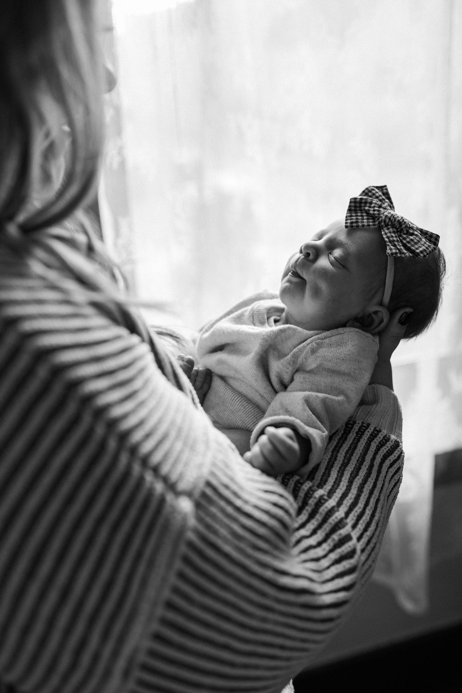 Black and white portrait series showing a person resting in striped clothing against a bright window background.