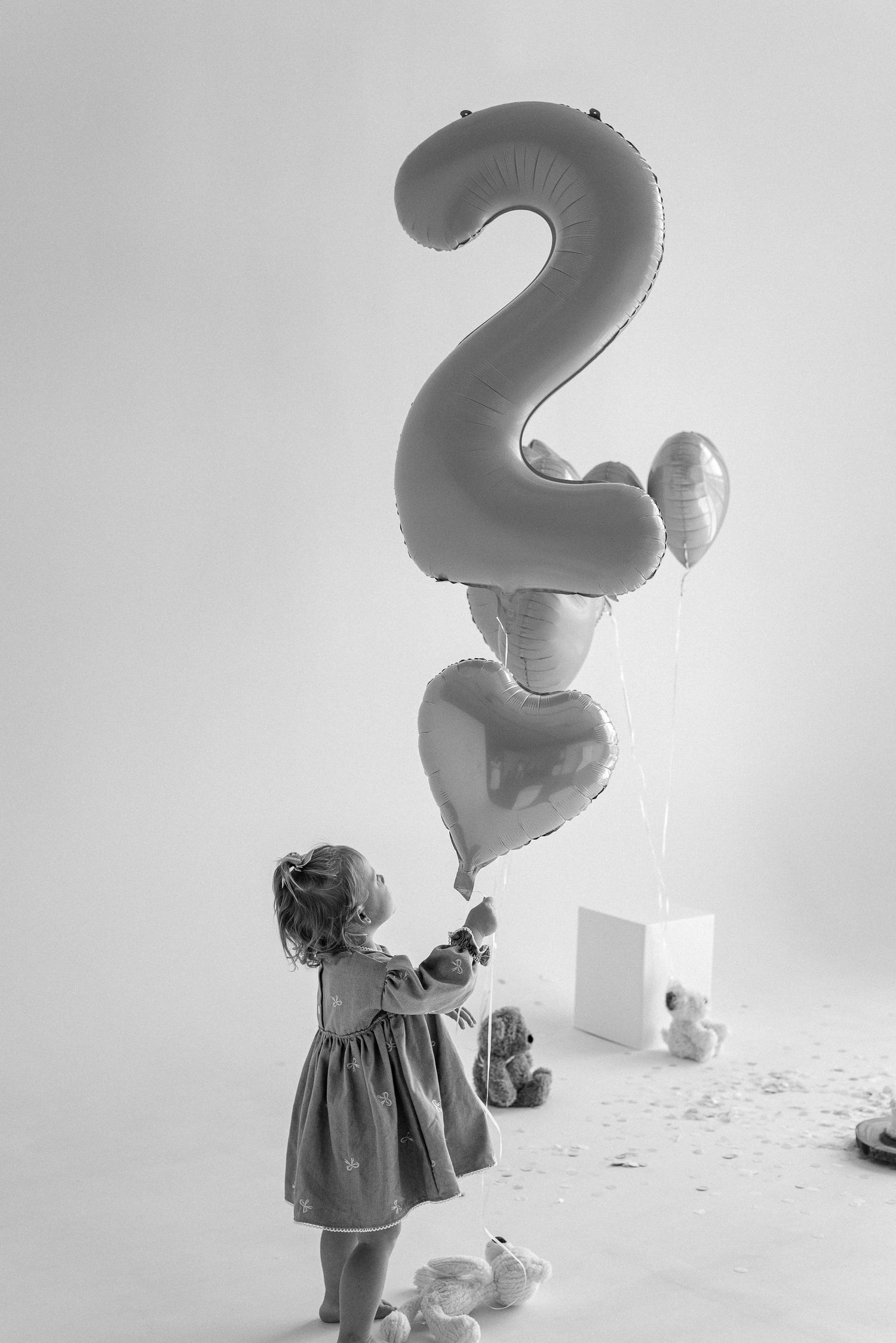A black and white photo series featuring a number 2 balloon and a birthday celebration setup.