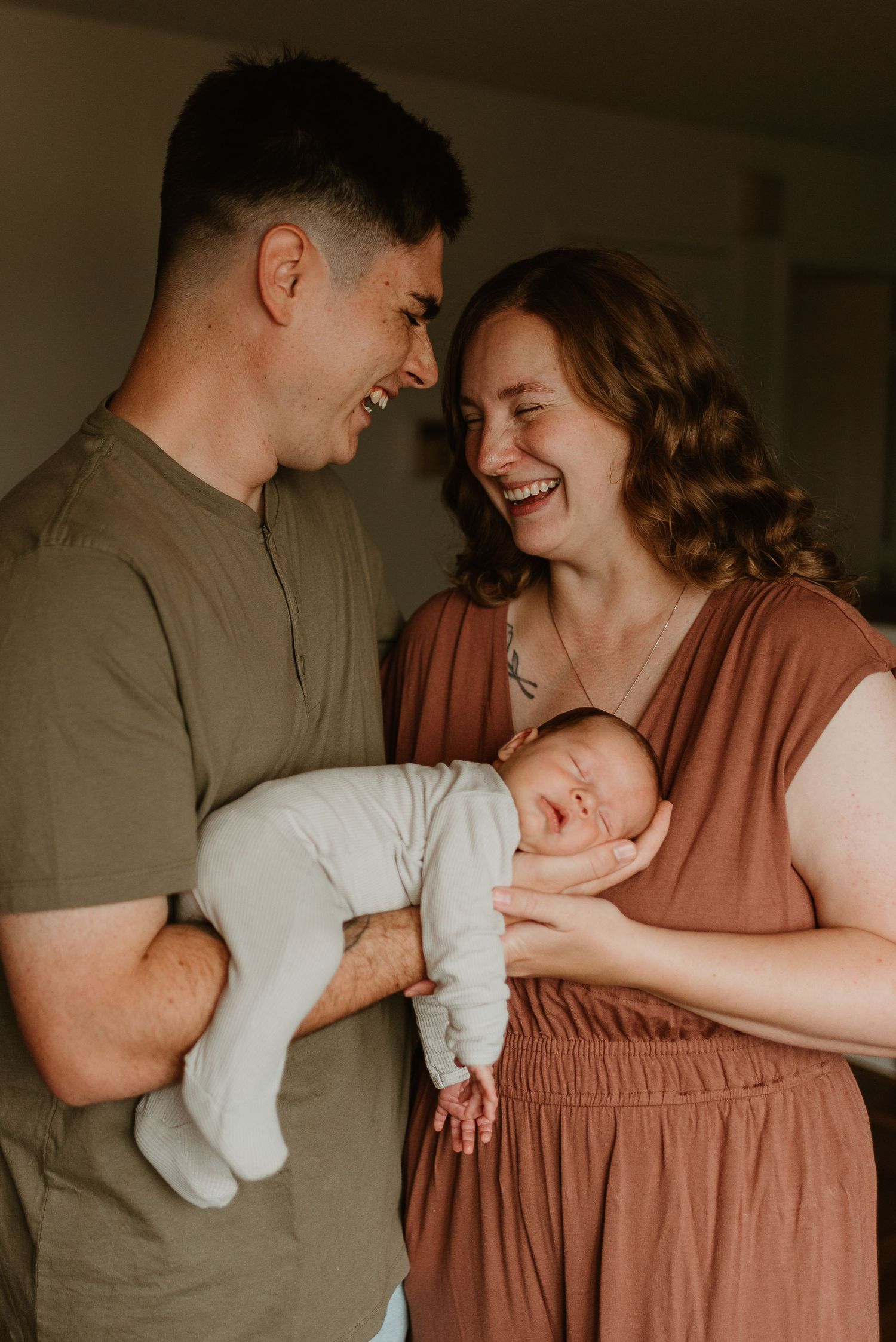 A couple in brown and gray clothing share tender moments with their newborn baby in a series of intimate portraits.