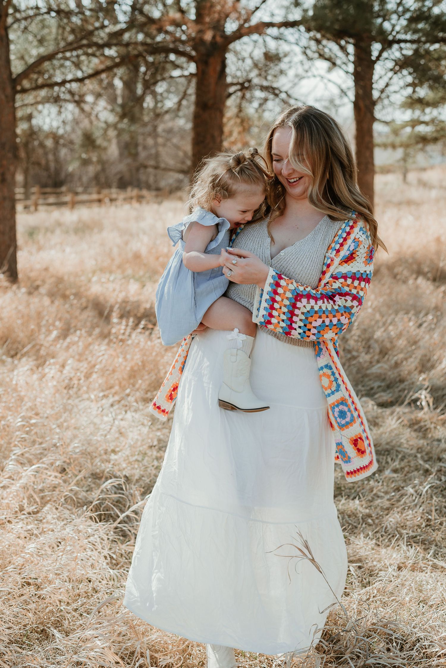 Sweet interaction between two people wearing coordinated outfits in a sunlit field.