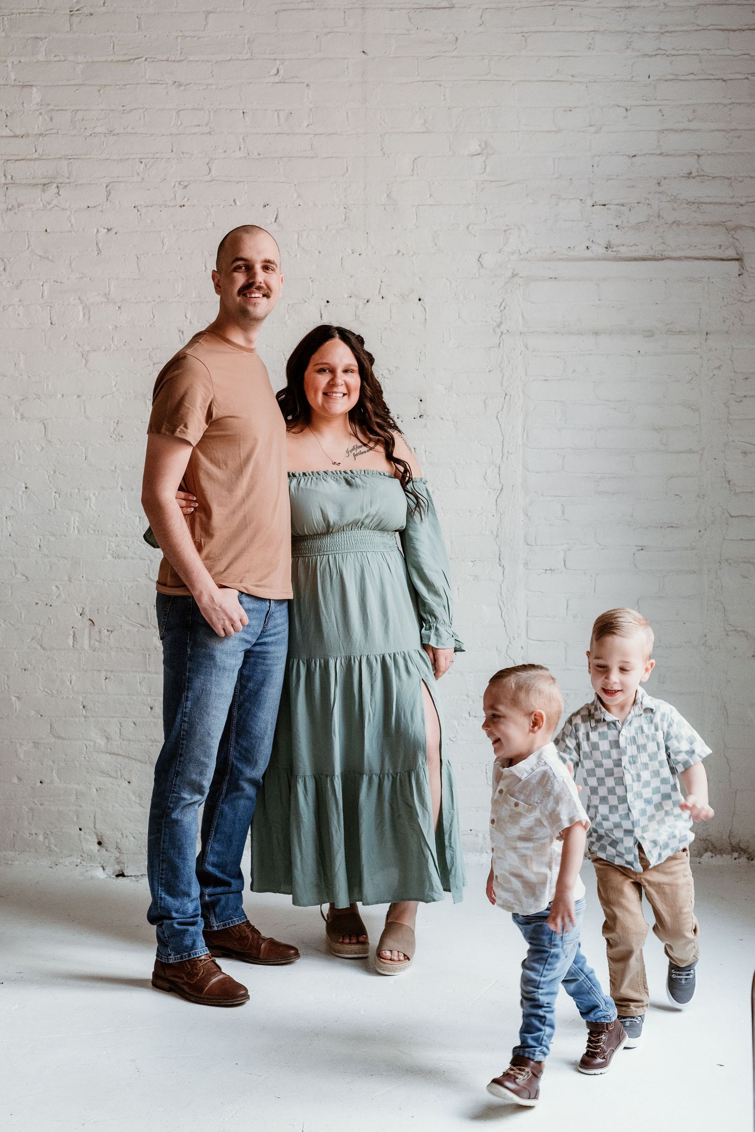 Family portrait series in sage green and neutral tones against white brick wall.