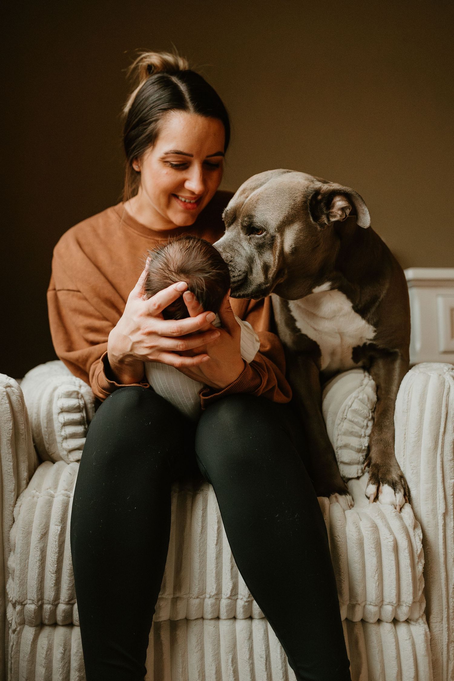 Person in orange sweater cuddling with a gray dog on a white radiator.