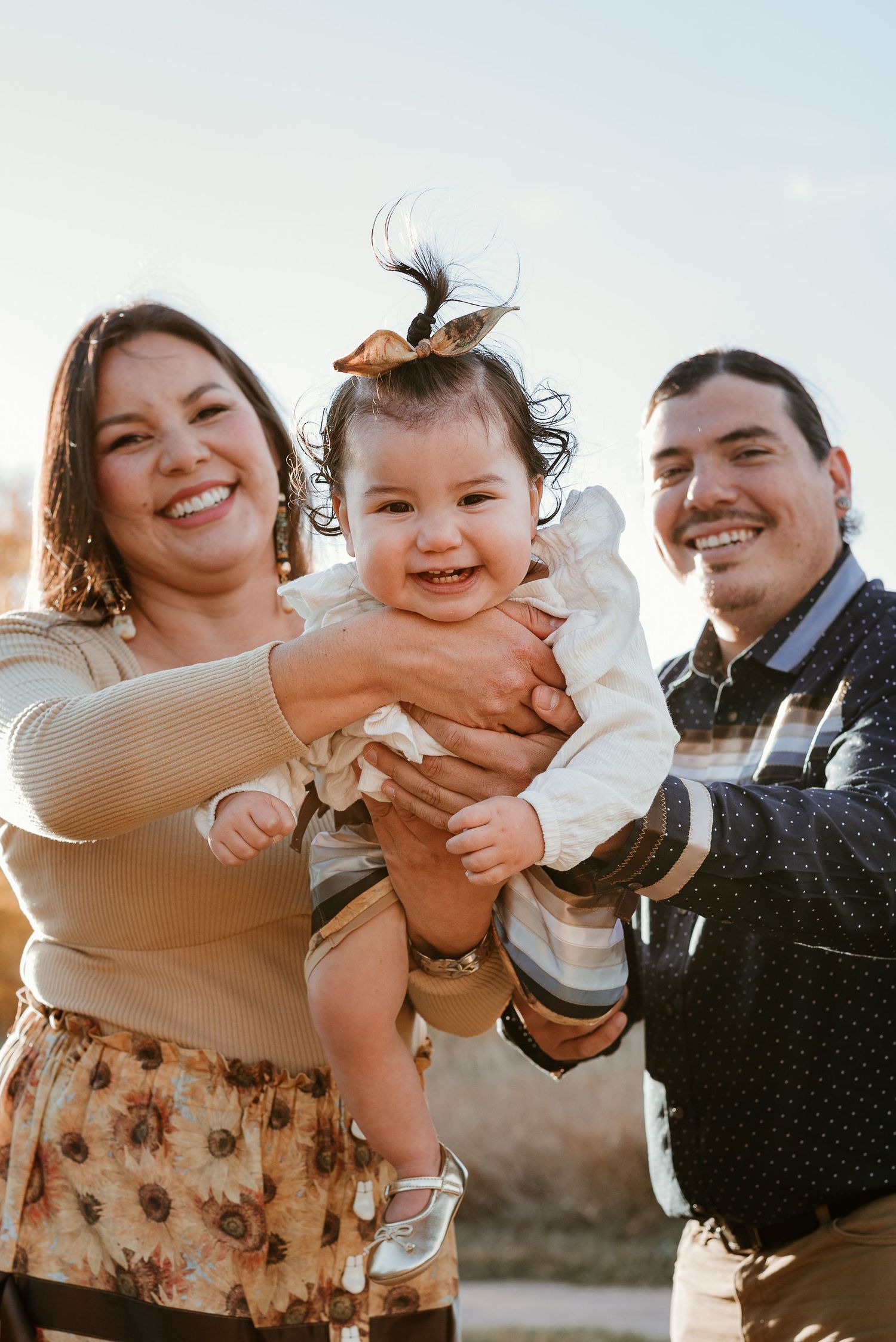 Candid family moment captured against bright sky during sunset photoshoot.