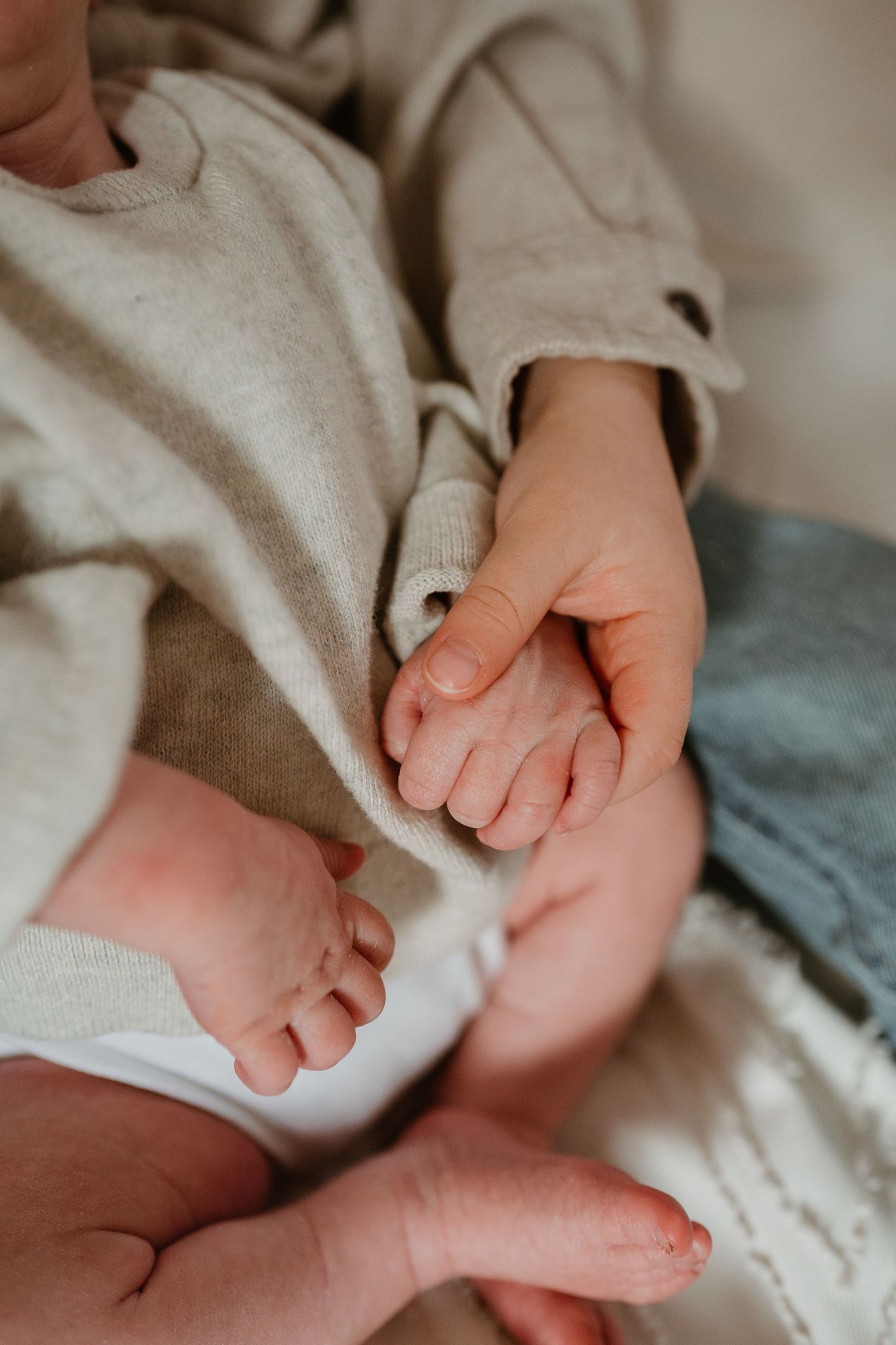 Close-up series of tiny baby feet and hands with delicate fingers against soft fabric textures.