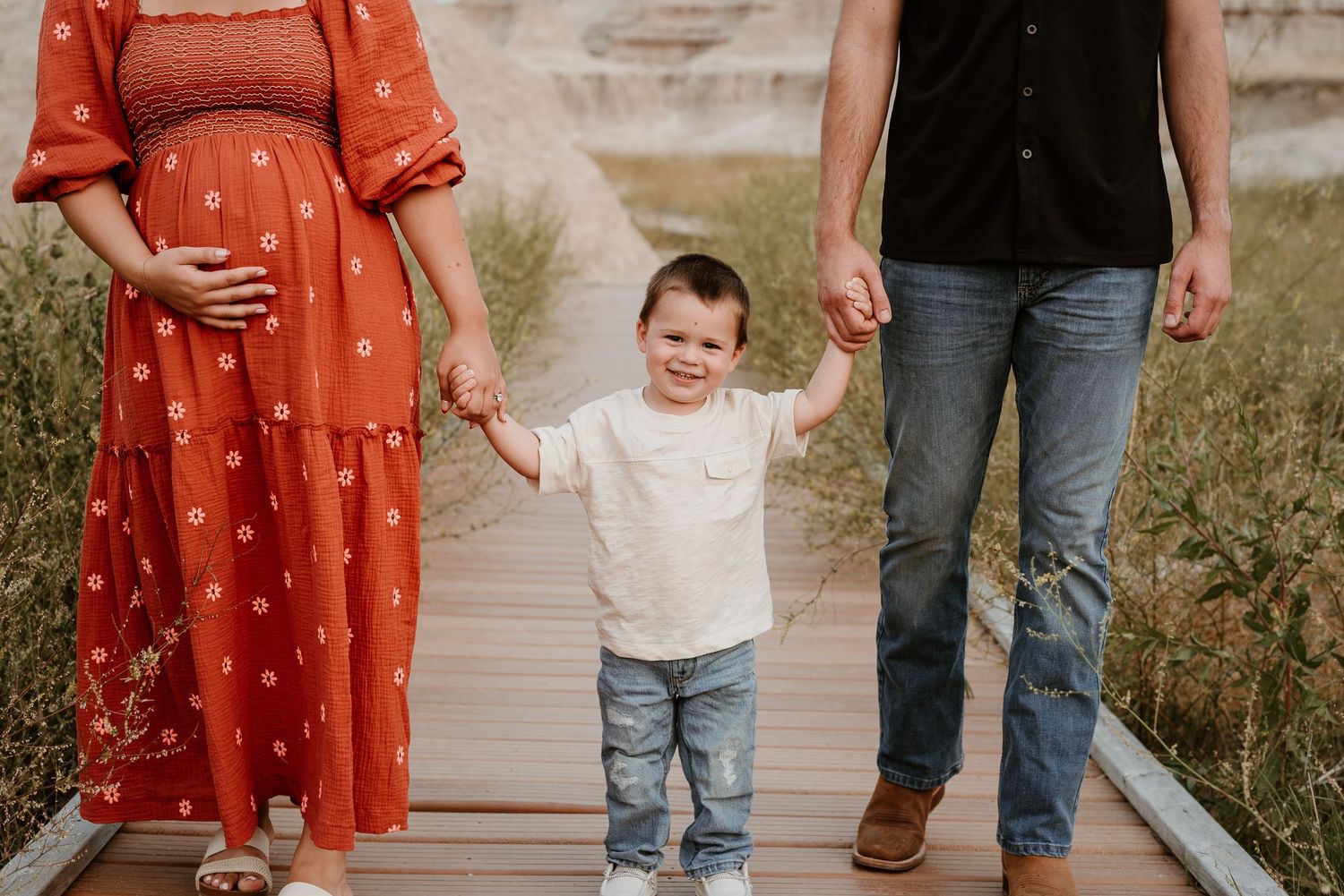 Family walking together on wooden boardwalk with red dress and casual attire.