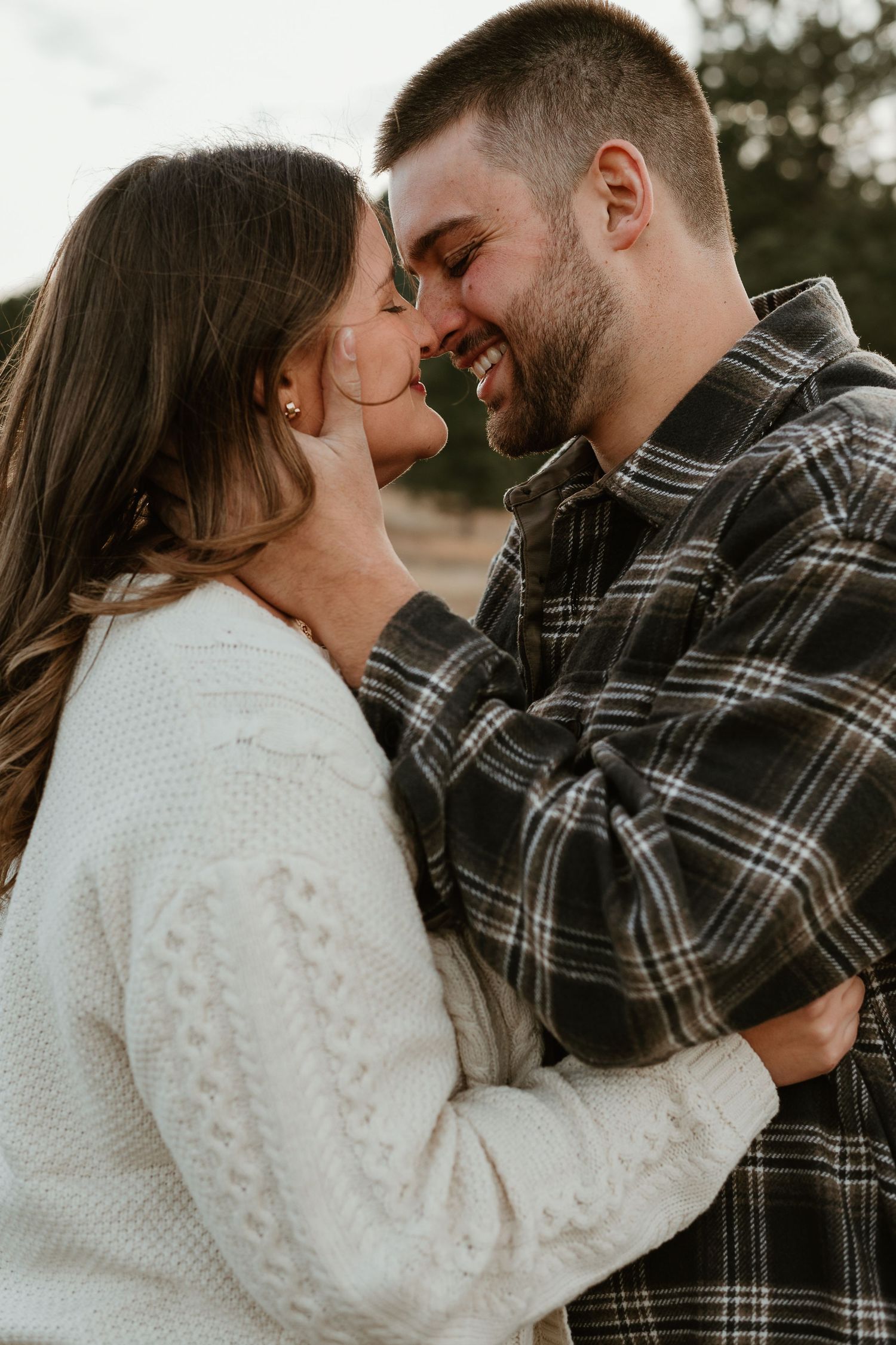 Romantic couple embracing while wearing plaid and white lace in an outdoor setting.