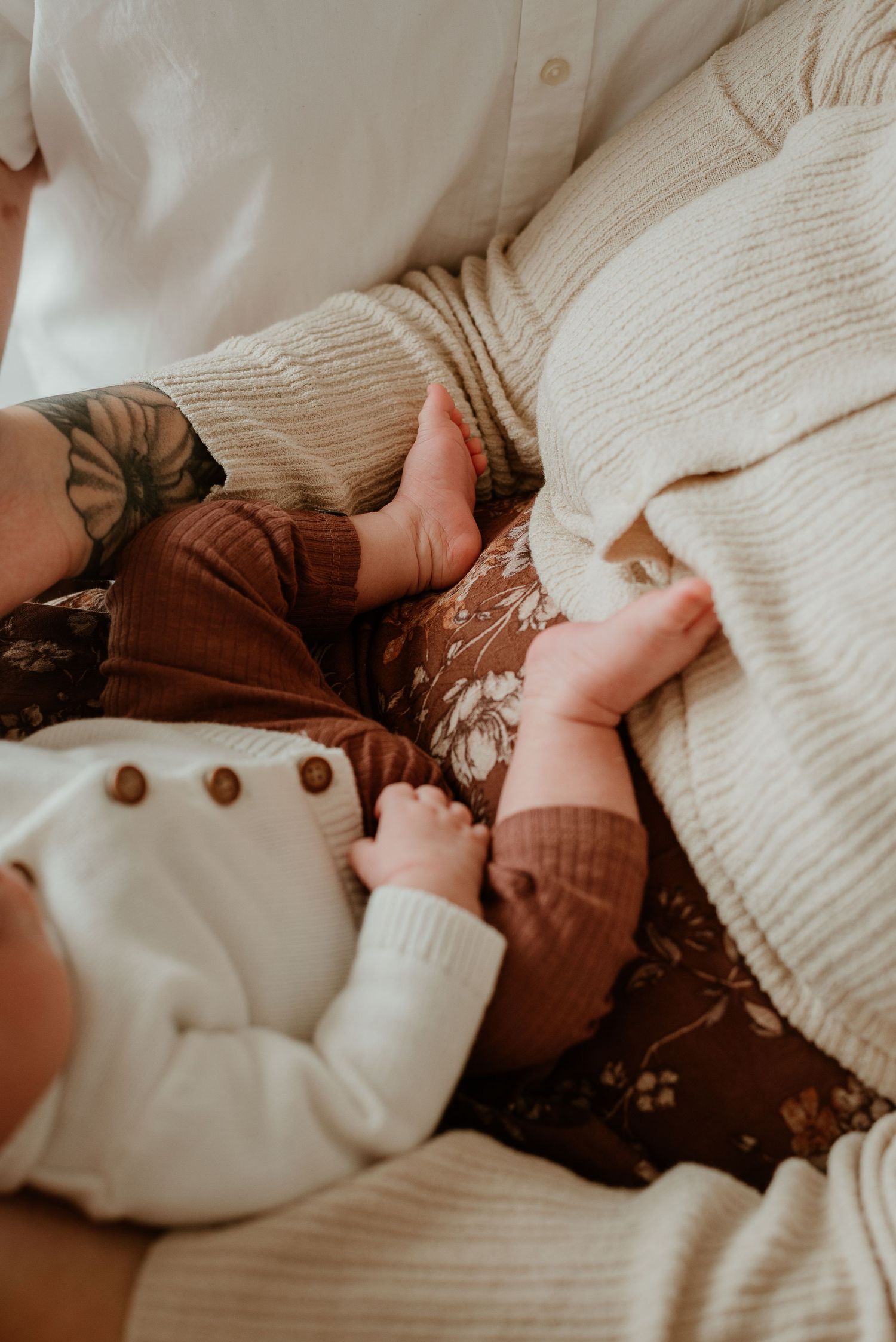 Close-up view of hands holding a white knit sweater with brown buttons against a cozy fabric background.