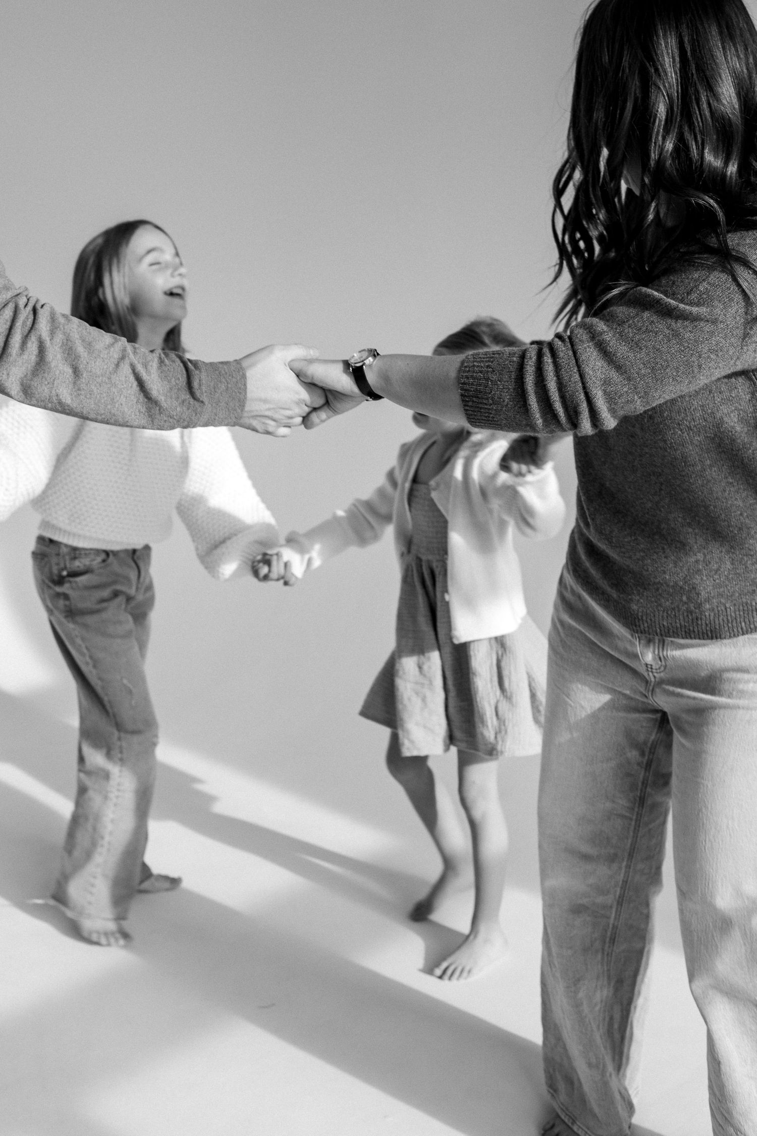 Sequence of black and white photos showing playful movement and dancing in a minimalist setting.
