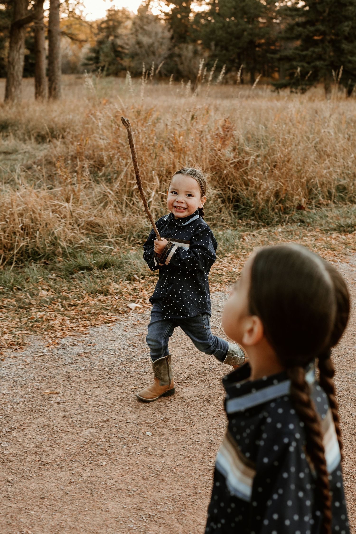 Children playing and running through a golden autumn field at sunset.