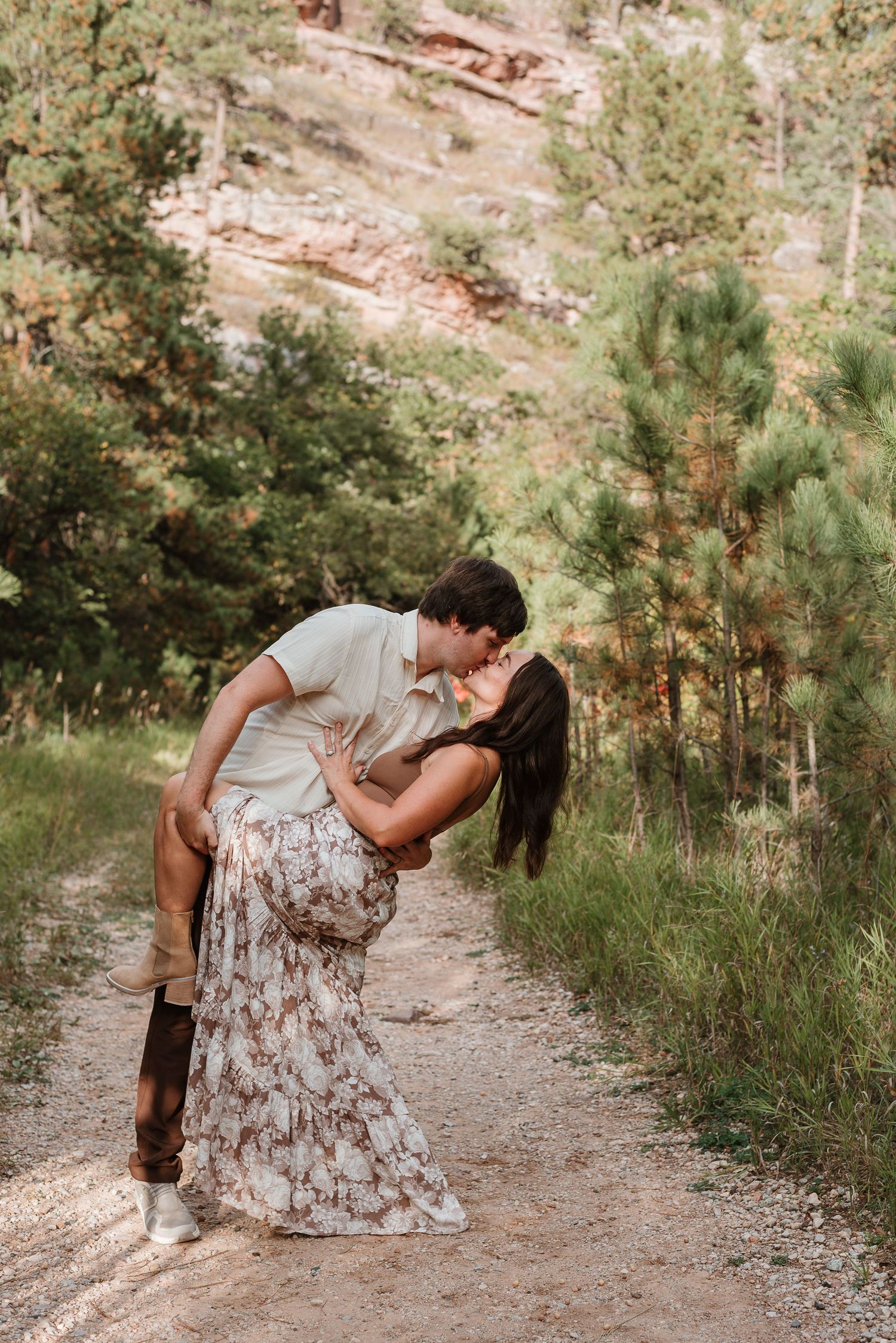A romantic couple dances together on a sunlit forest path while sharing a tender dip pose.