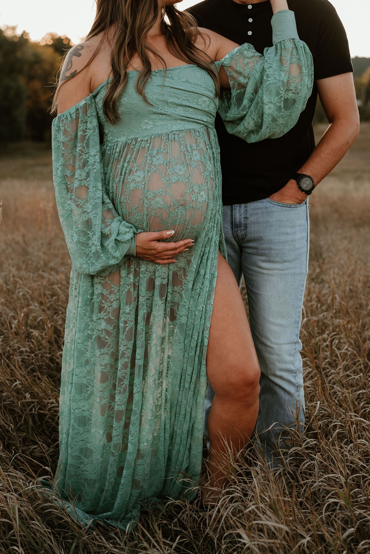 Couple embraces in a field at sunset, with her wearing a flowing mint lace dress.