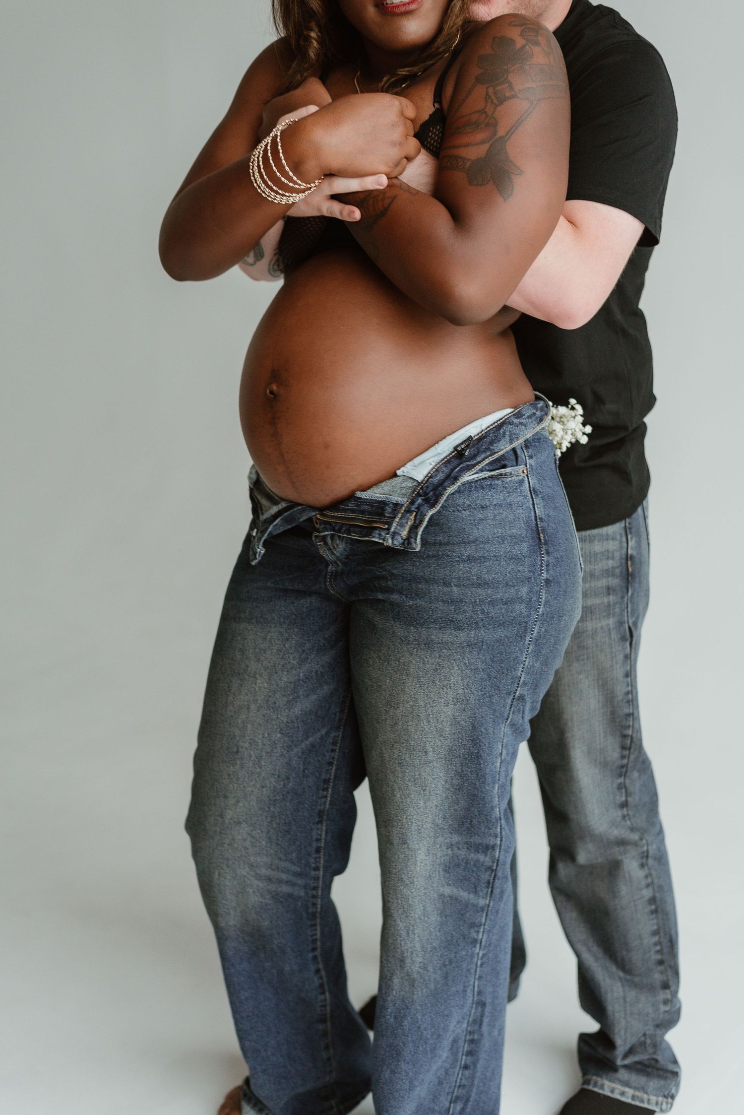 A series of intimate maternity photos showing a couple embracing in casual denim against a white background.