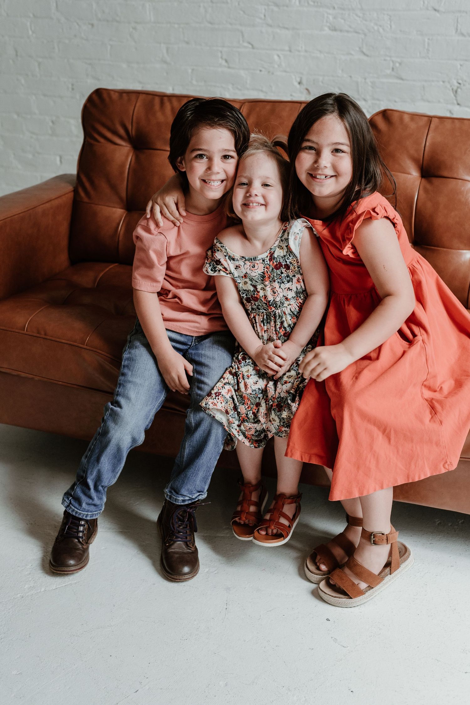 Close-up of feet and legs of family members sitting on brown leather couch.