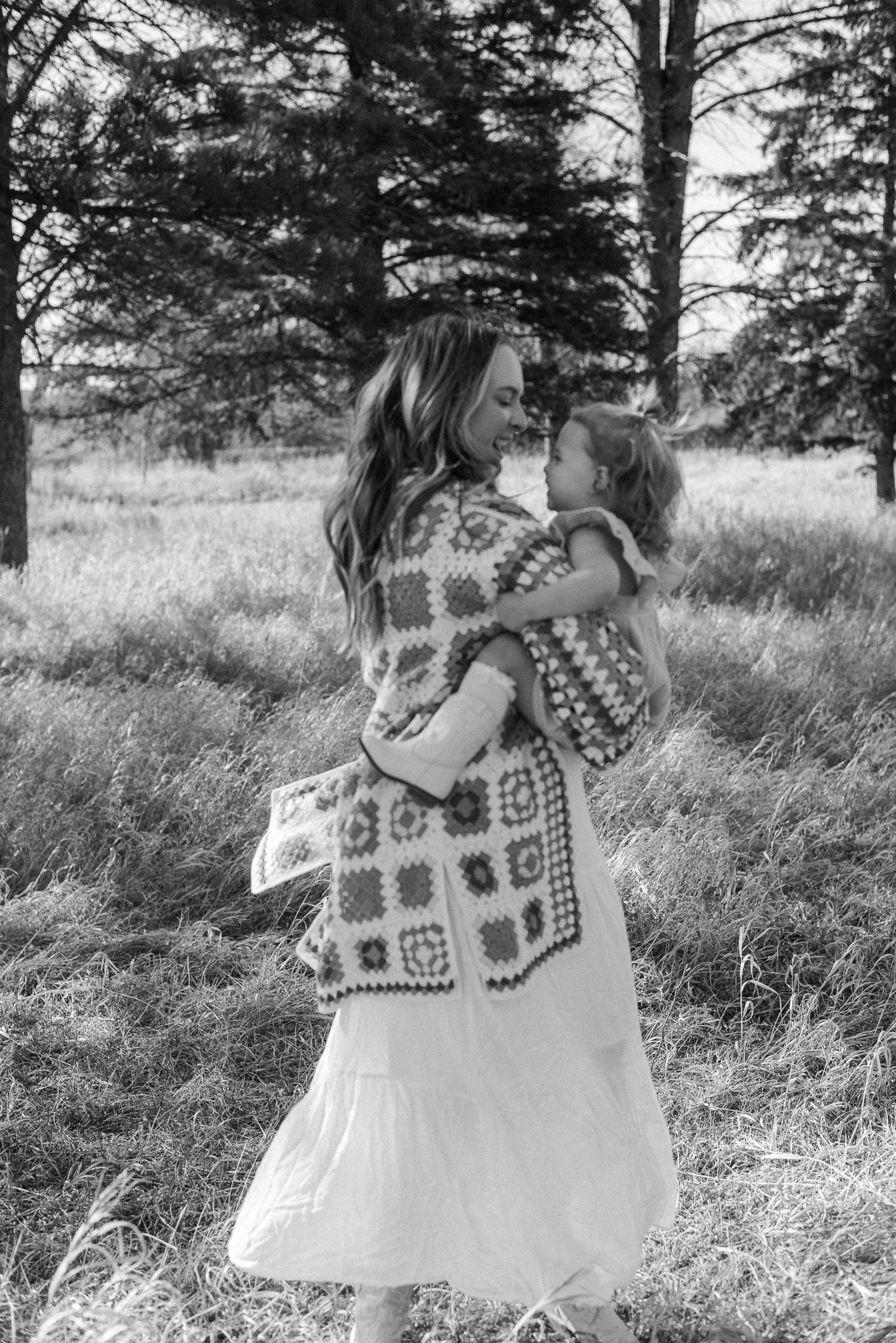Dancing in a field wearing a colorful granny square cardigan and flowing white dress.