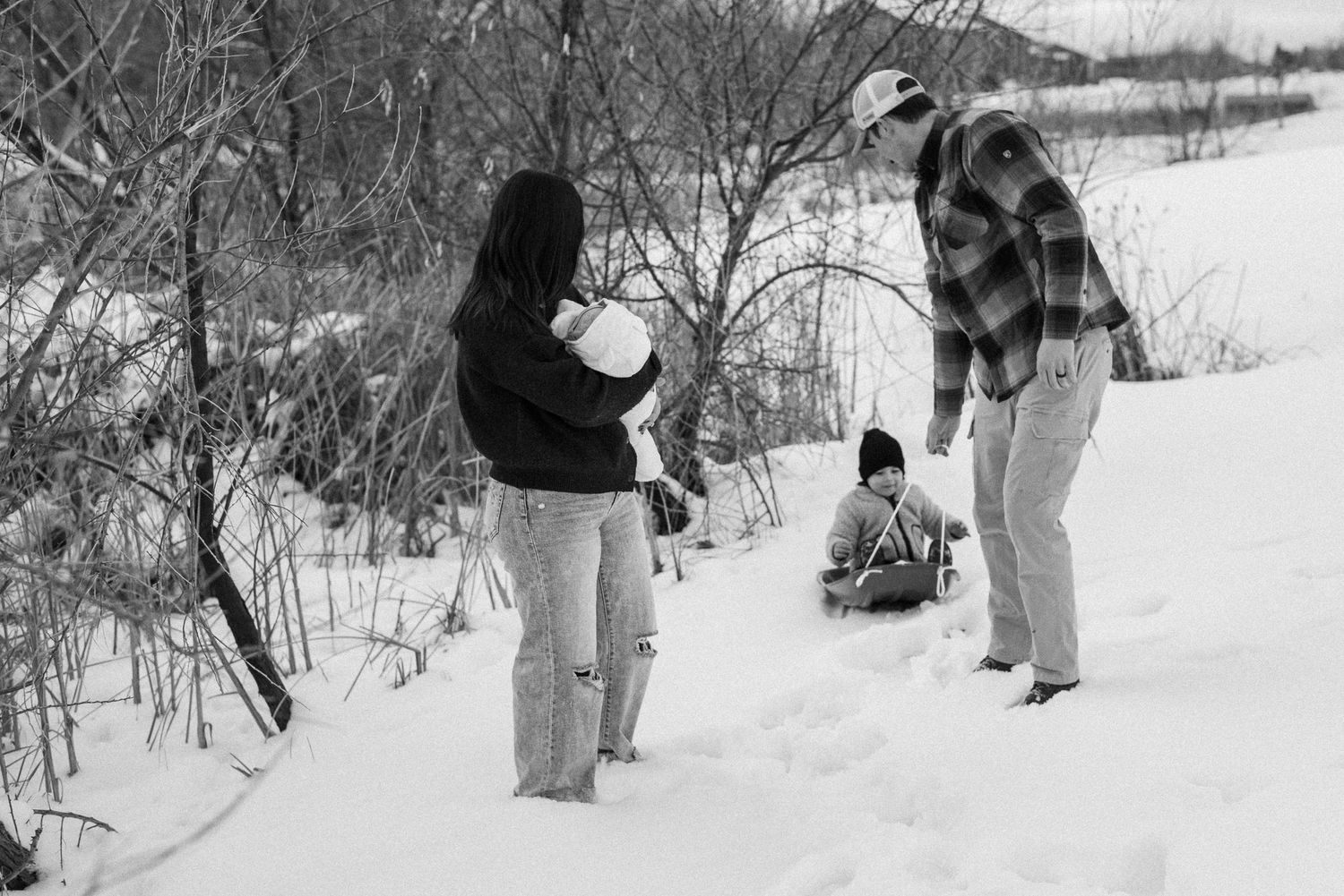 Black and white photo of a family enjoying a winter day in the snow together.