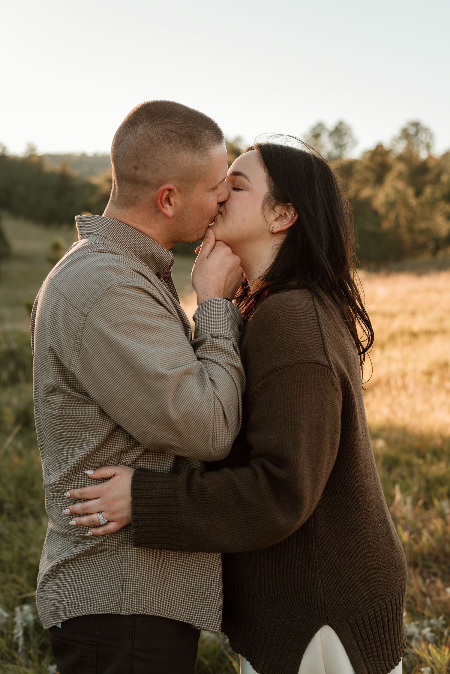 Intimate couple sharing tender moments in a sunlit meadow during autumn.
