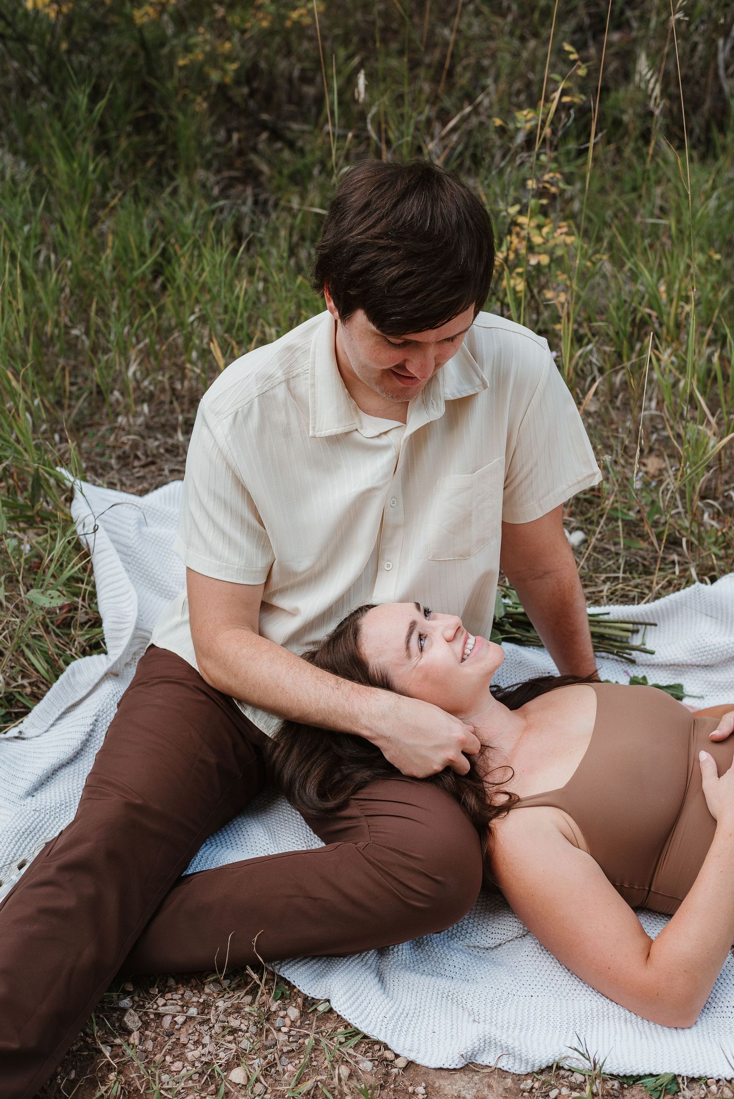 A couple lying on a blanket outdoors share intimate moments in a series of three romantic photos.