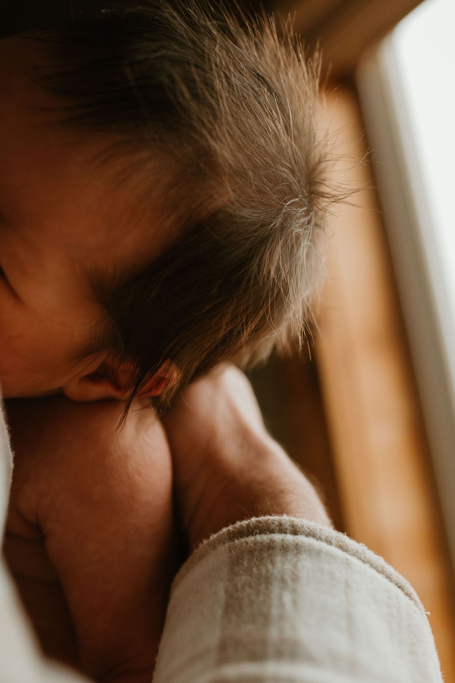 A tender moment captured in warm lighting shows a parent and baby in a gentle embrace.
