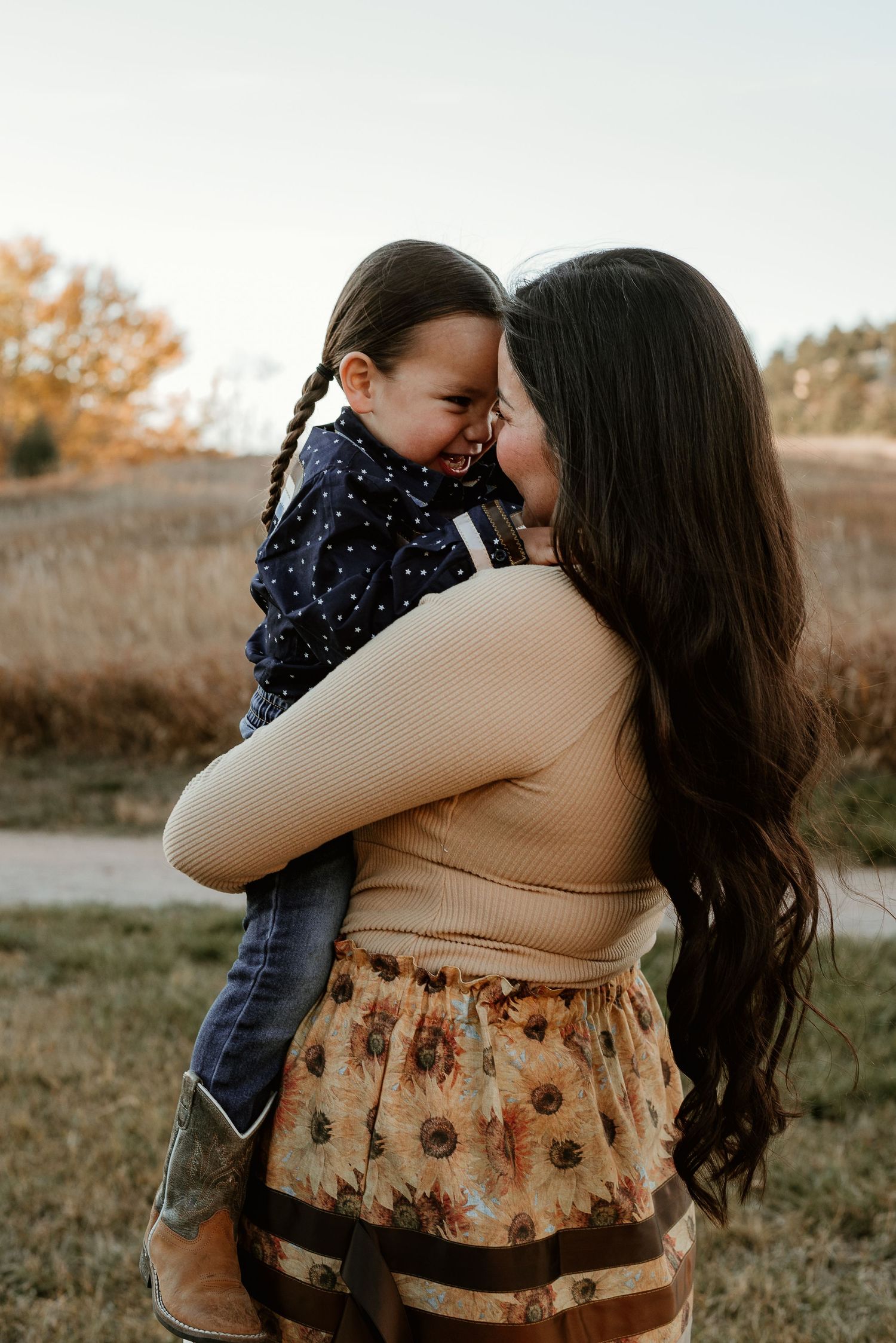 Intimate family moment captured during sunset in a field with autumn colors.