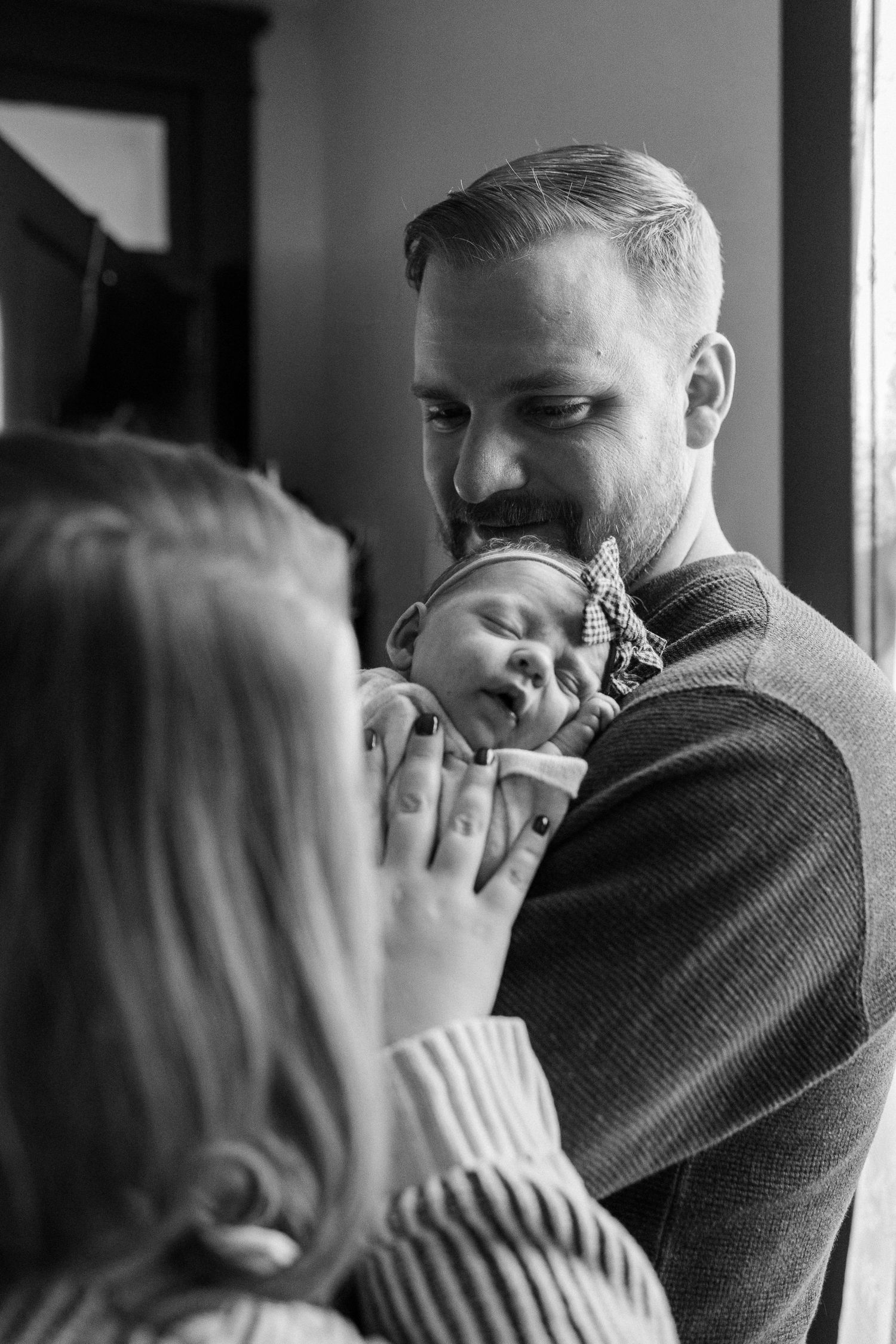 Black and white portrait of tender family moment with newborn baby.