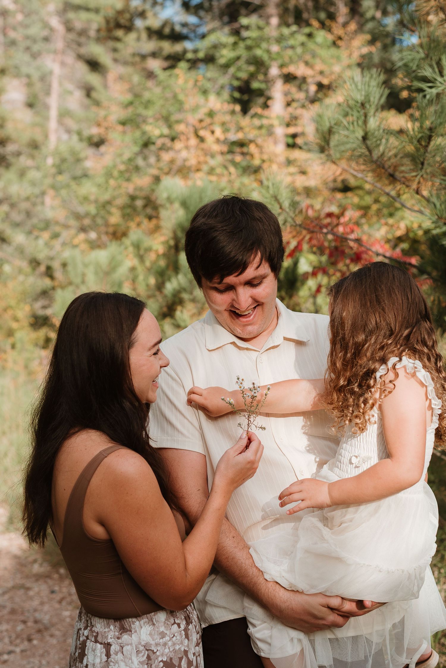A family shares a joyful moment together in a forest setting during a sunny autumn day.