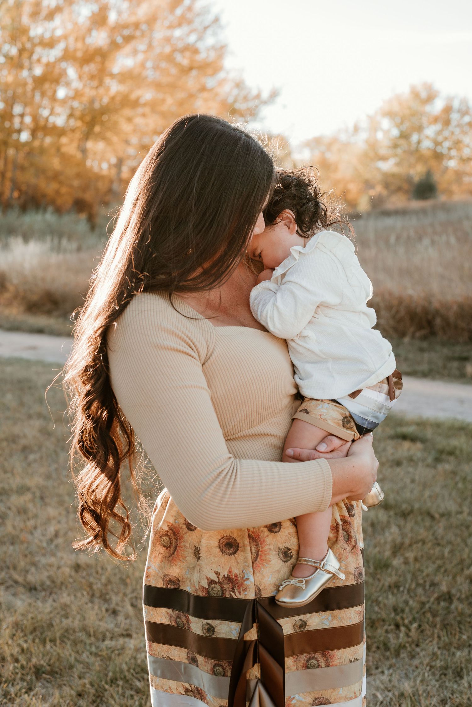 A warm autumn portrait showing affection between parent and child in a natural outdoor setting.