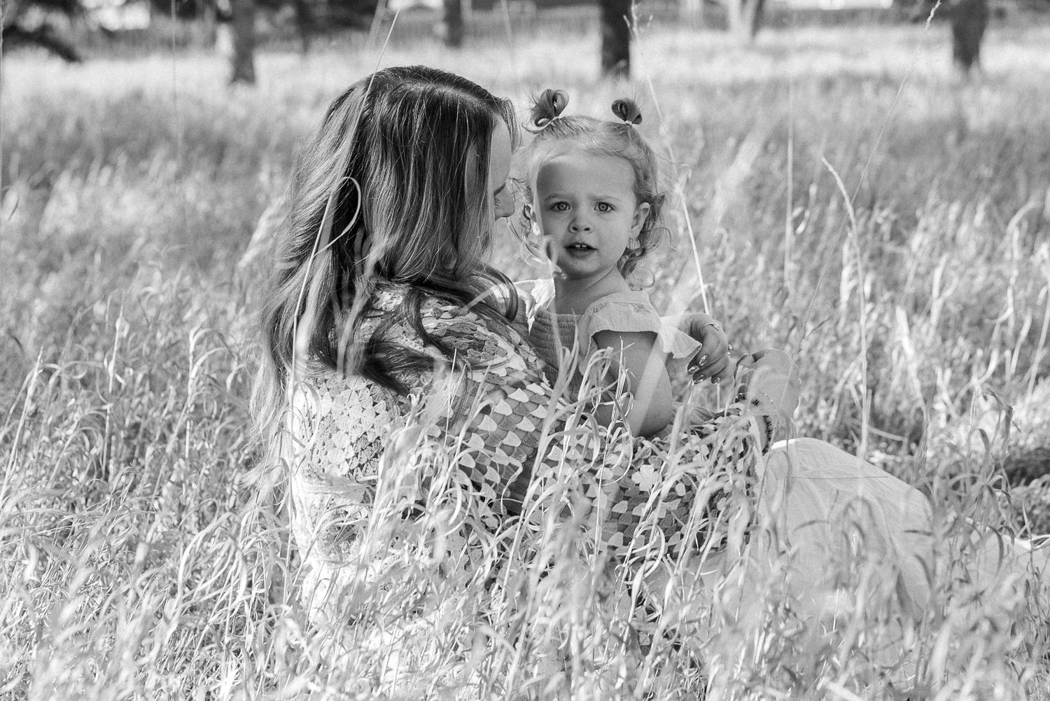 A tender moment captured in a field with someone wearing a colorful crocheted cardigan.