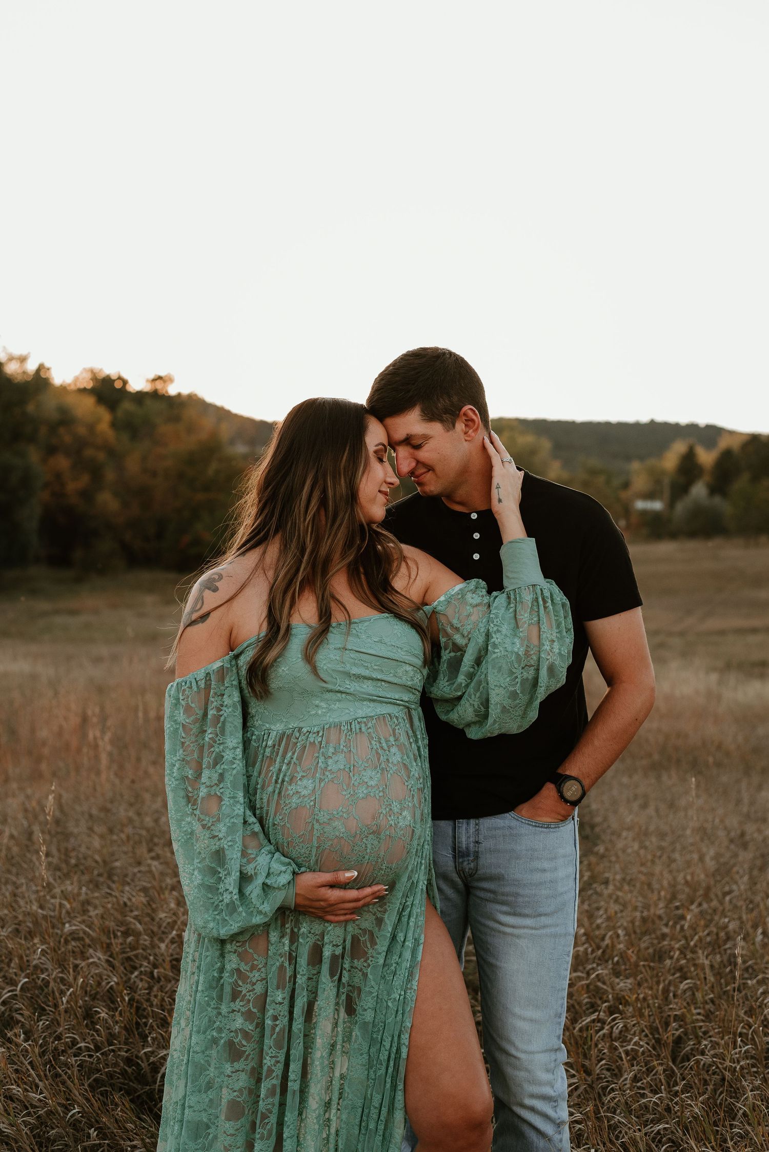 An intimate maternity portrait in a field with a mint green flowy dress at golden hour.
