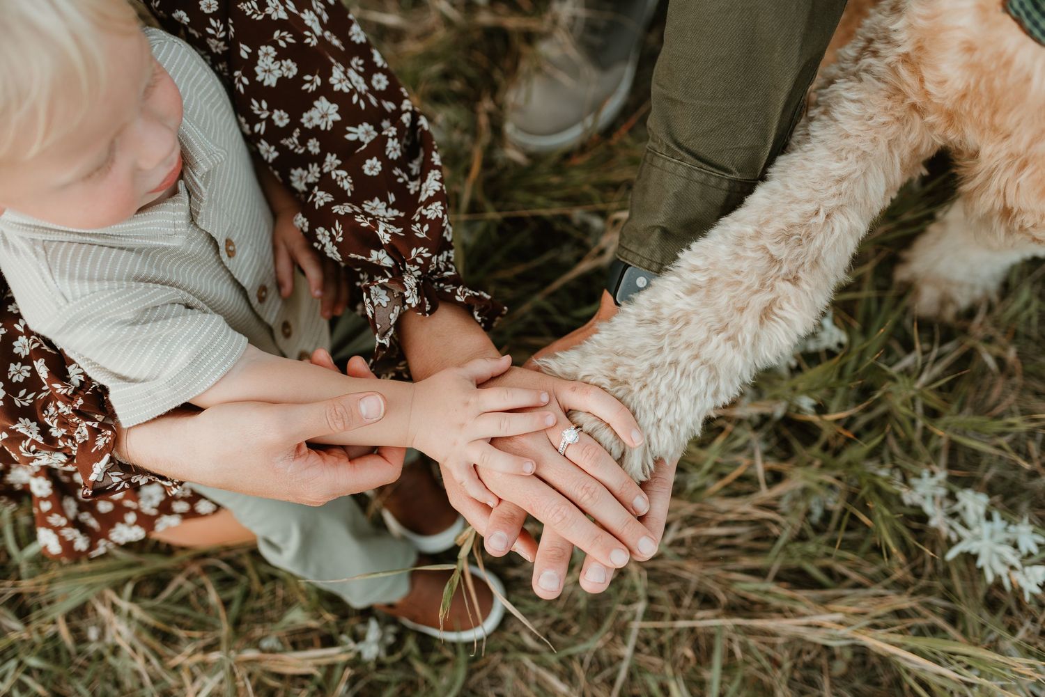 Close-up view of hands holding delicate lace wedding dress fabric against a natural outdoor background.