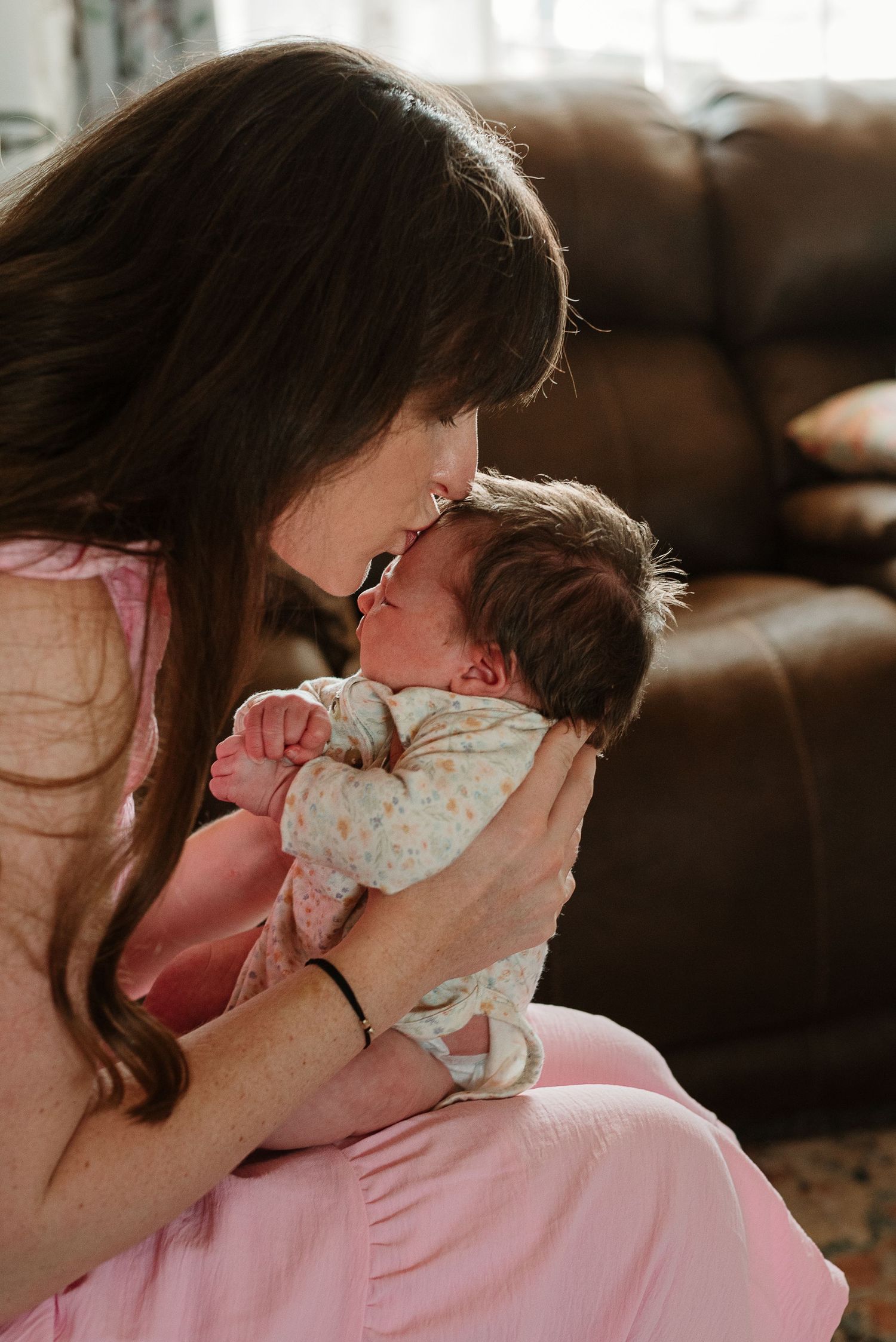 A tender moment between parent and baby in warm sepia tones showing loving connection and gentle embrace.