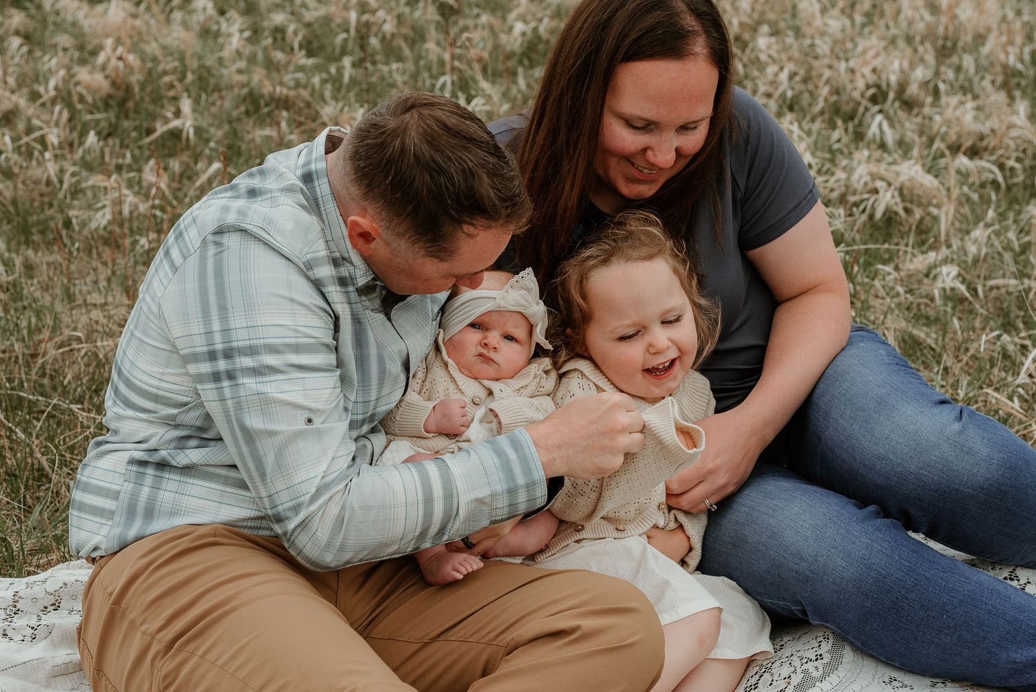 A family shares an intimate moment together on a blanket outdoors.