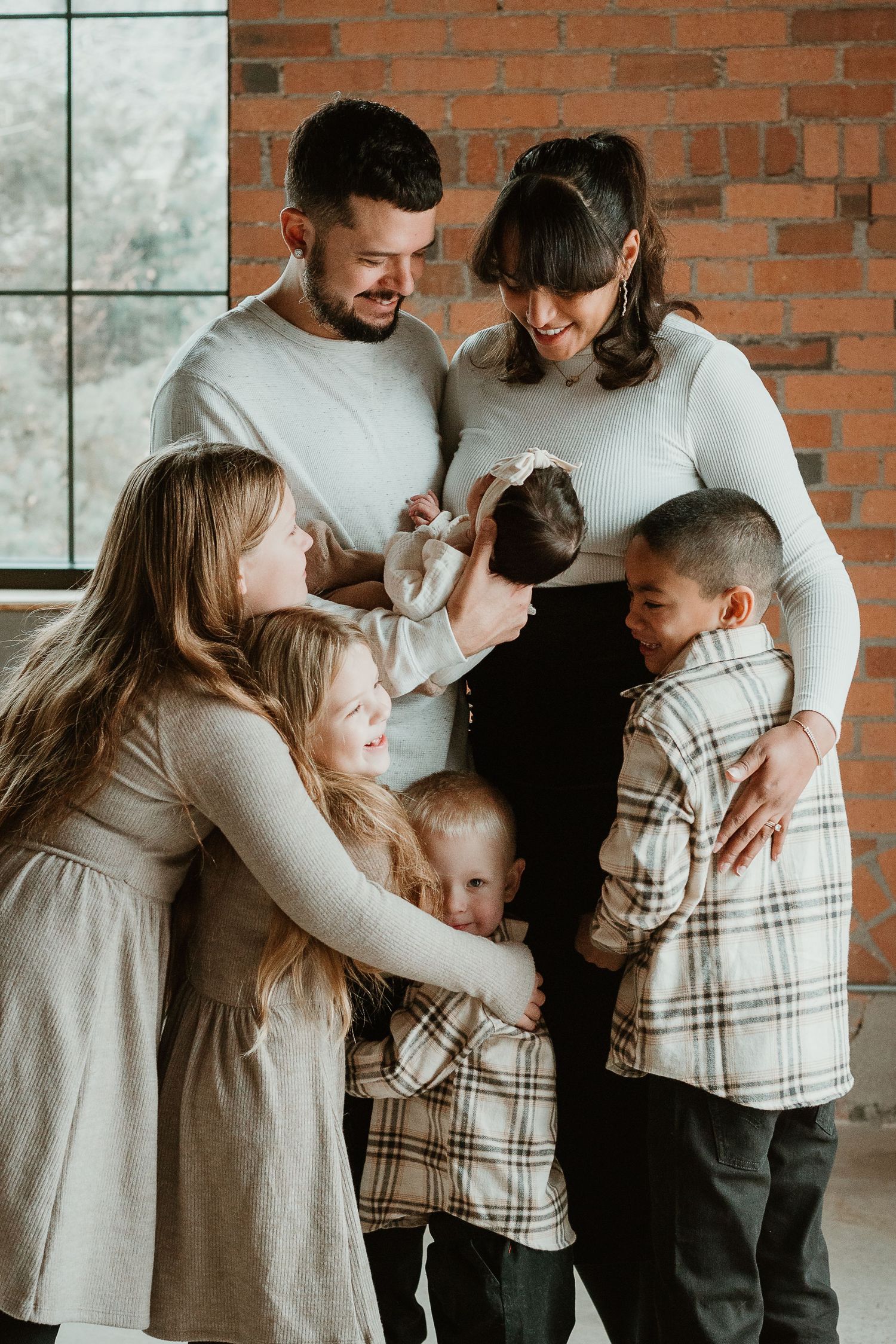Intimate family portrait with everyone dressed in neutral tones sharing tender moments together.