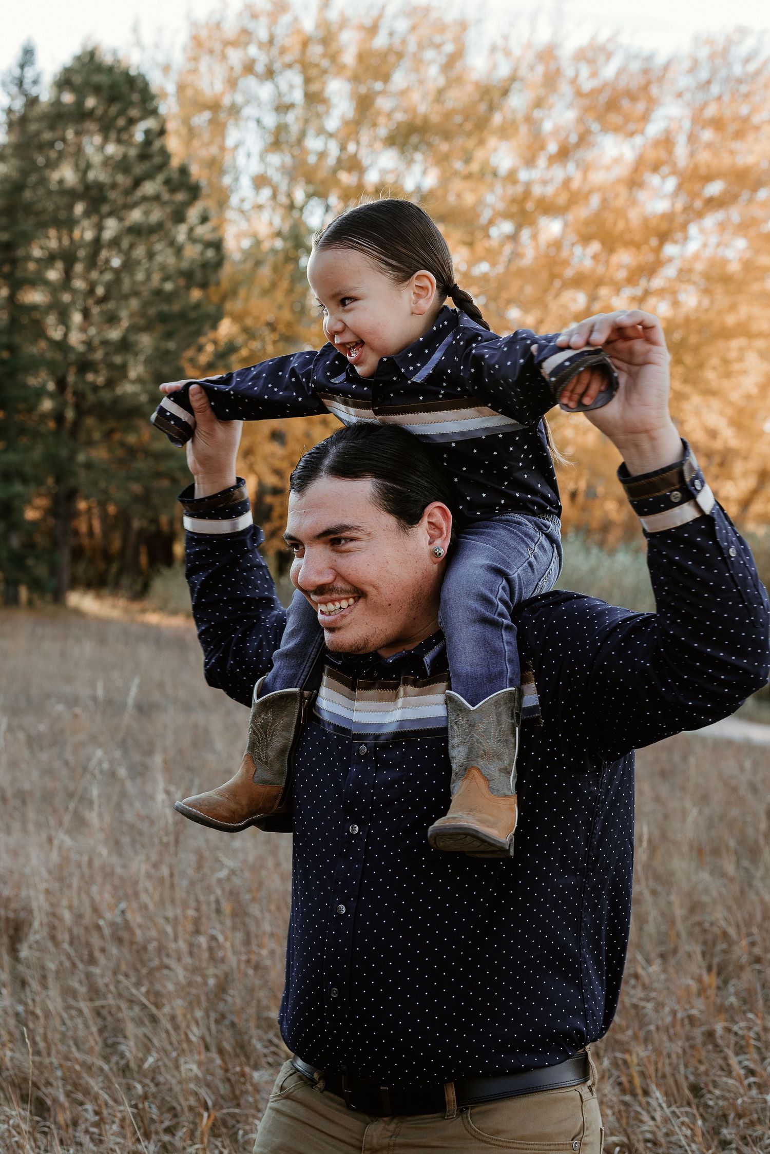 Person in navy polka dot shirt playing and having fun in autumn field.