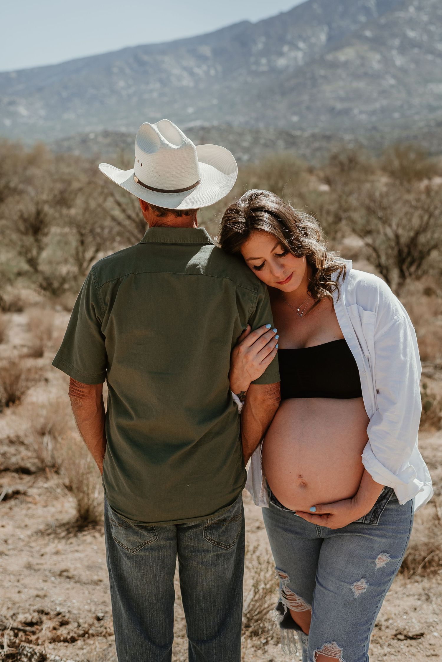Intimate desert maternity session with mountain backdrop and natural lighting.