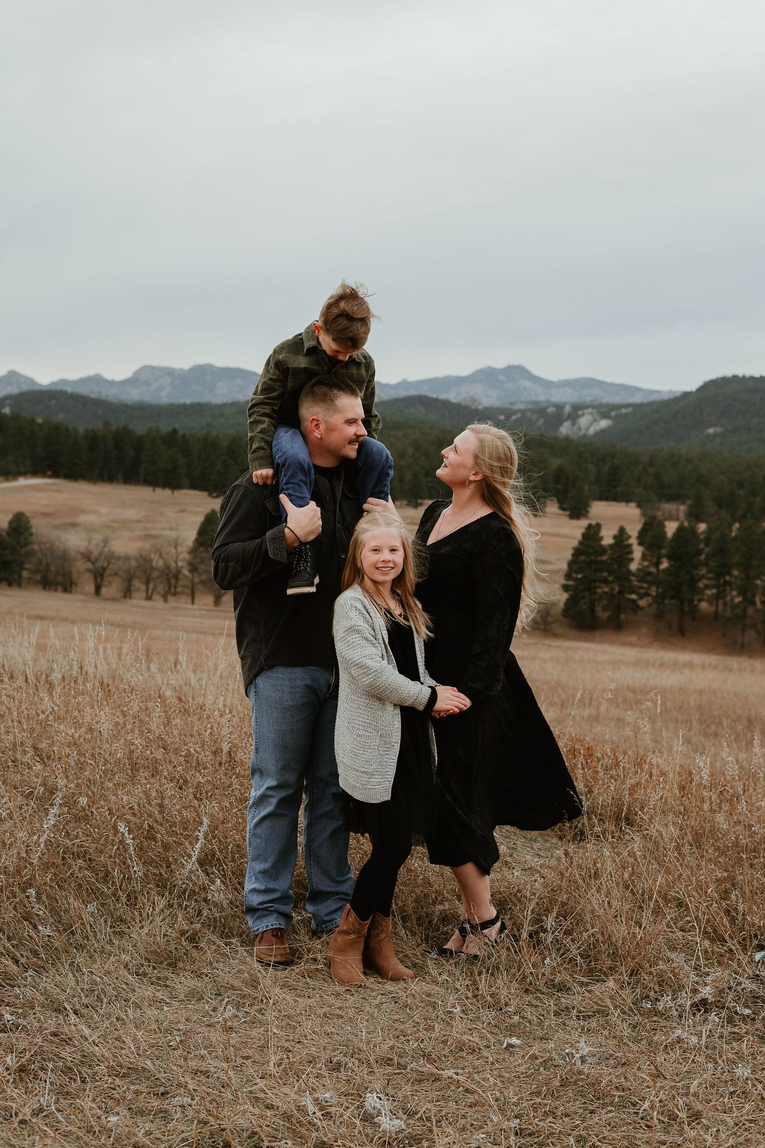 A family sharing joyful moments together in a scenic mountain meadow during autumn.