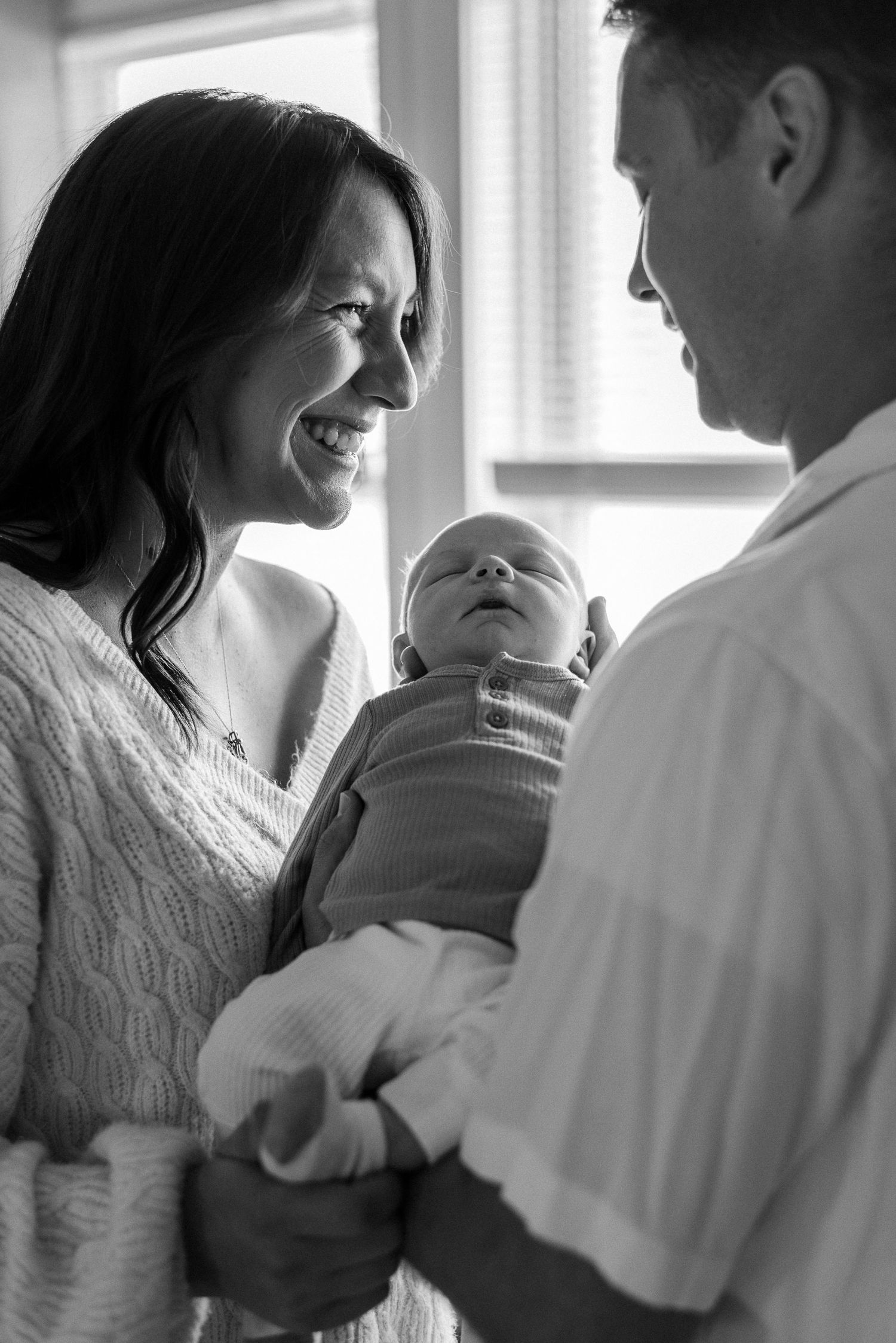 A tender moment between parents and their newborn baby shown in black and white.