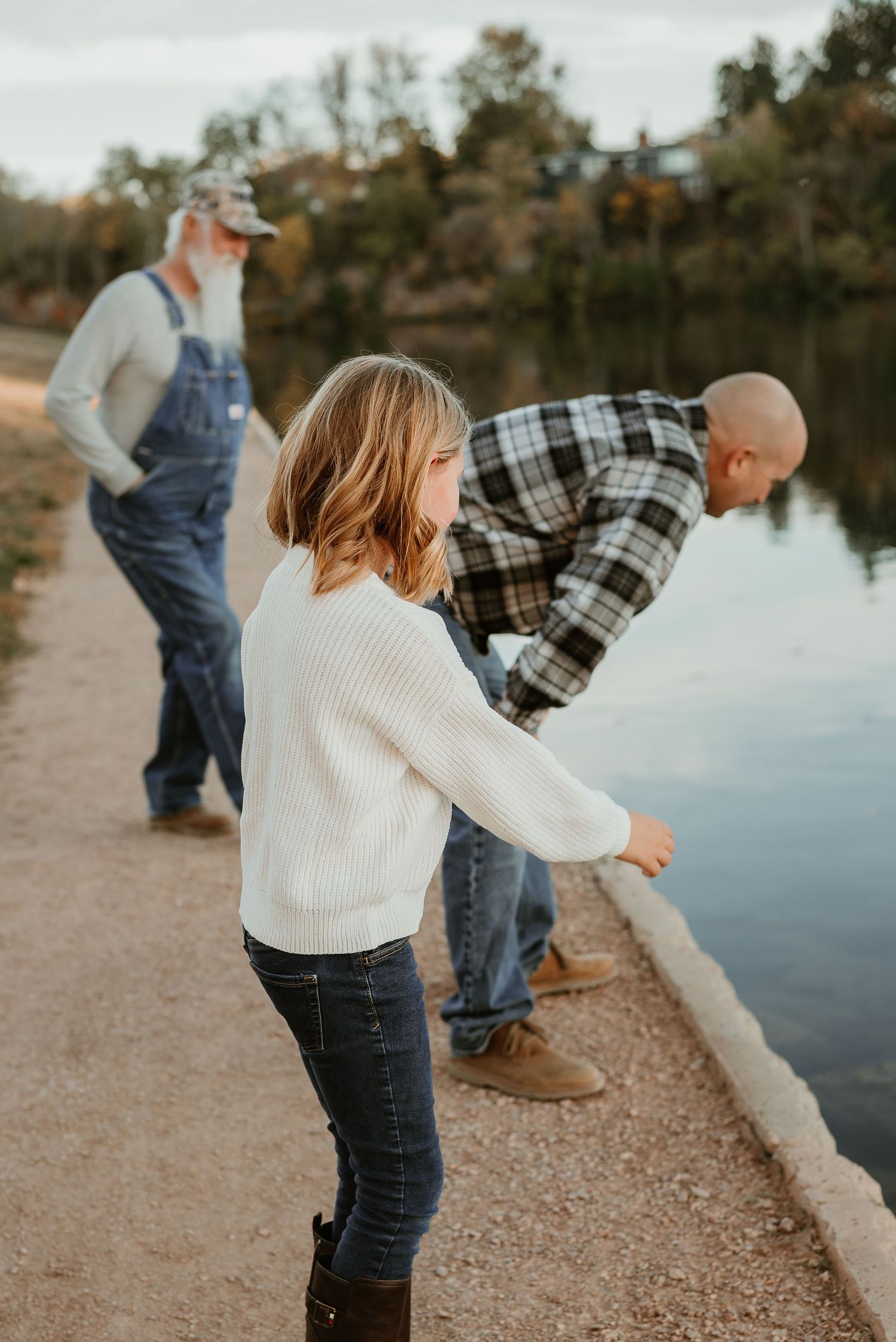 Playful moments by a lake during sunset with family members.