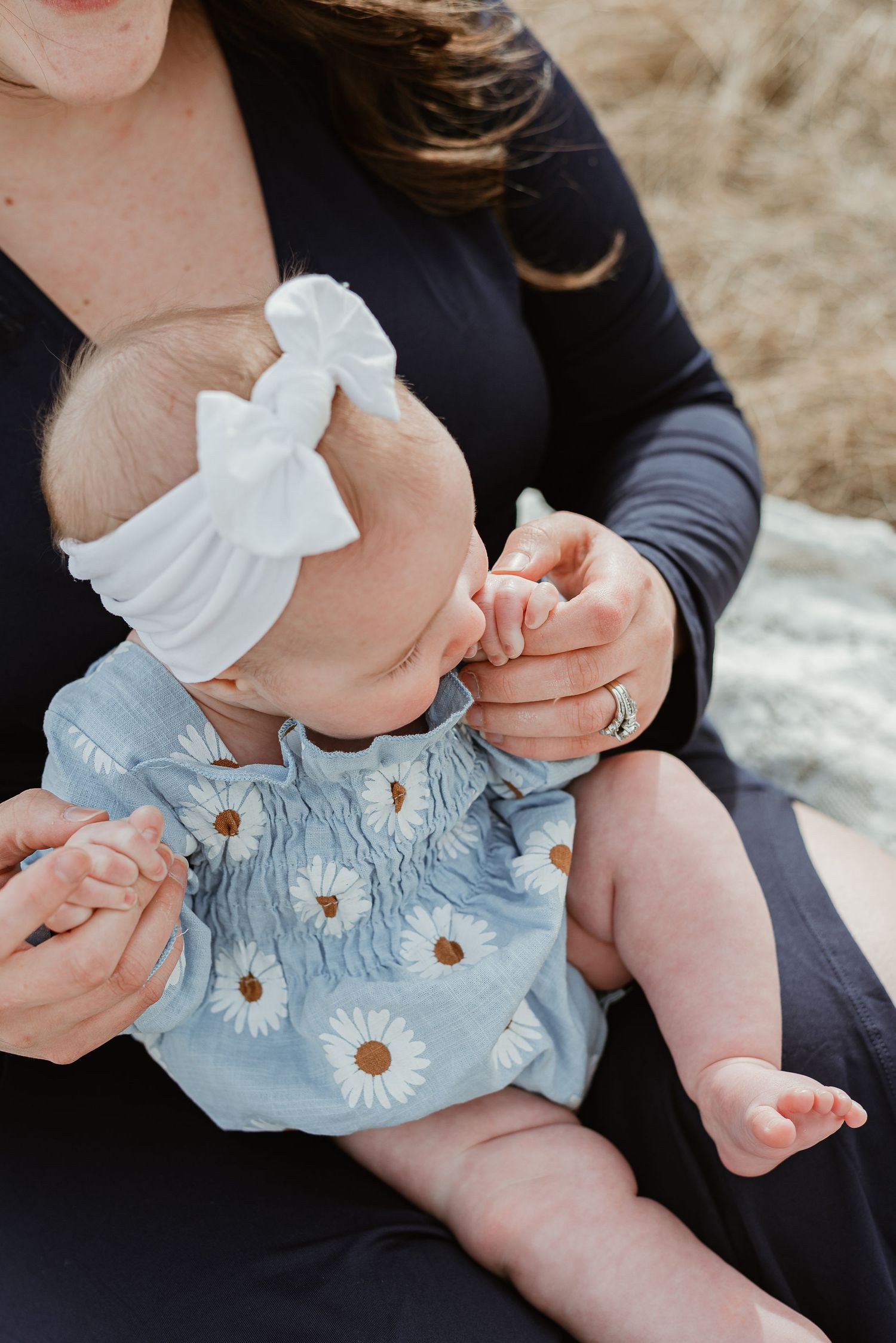 Close-up details of baby wearing light blue smocked dress with daisy embellishments.