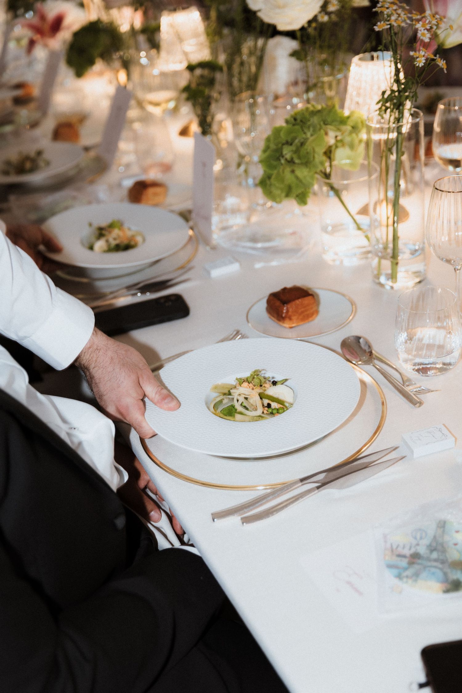 Elegant table settings at a fine dining restaurant with white plates, glassware and delicate floral arrangements.
