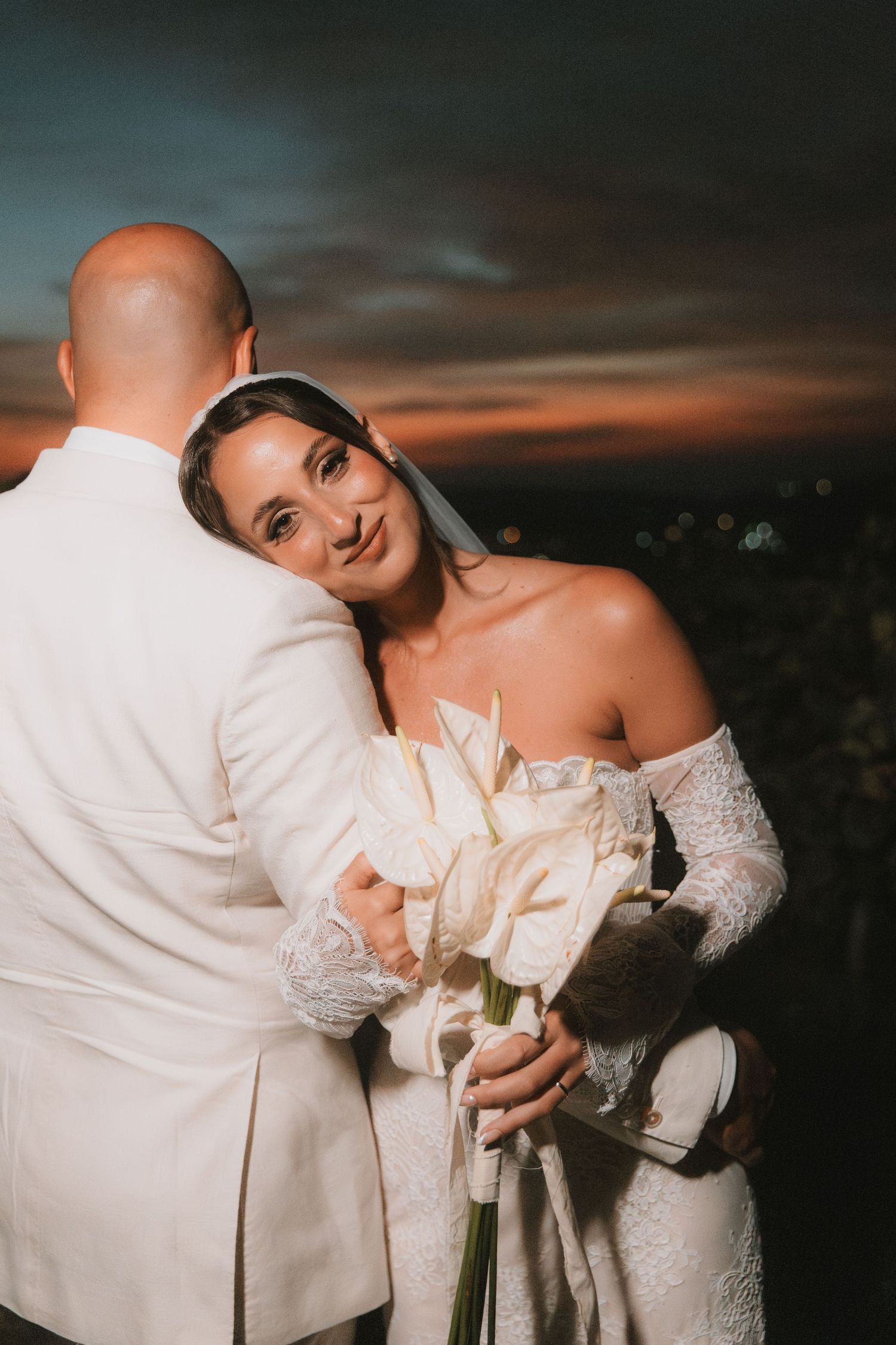 Romantic wedding portrait at sunset with couple in white formal attire.