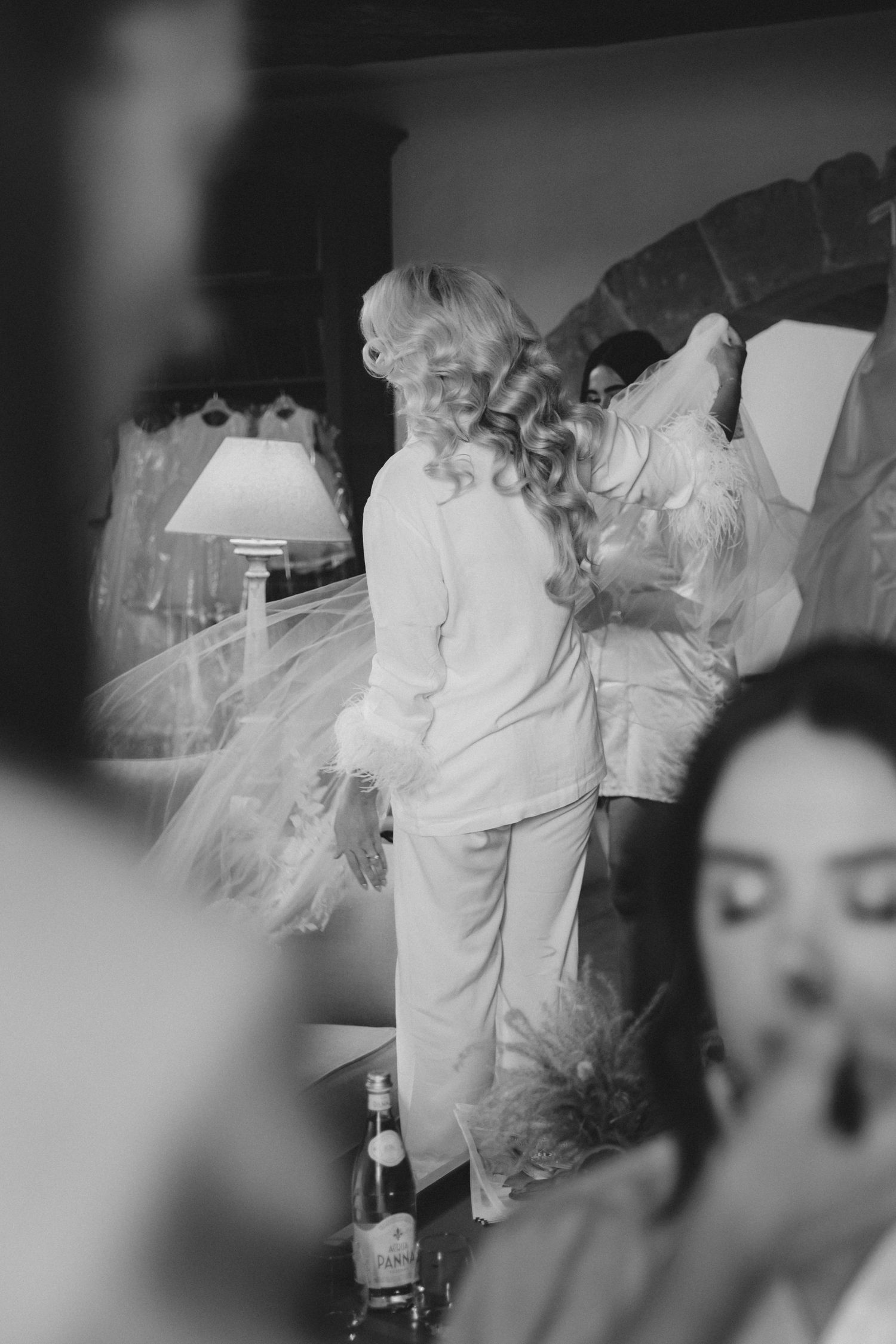 A candid black and white photo showing wedding preparations with a figure in white silk pajamas.