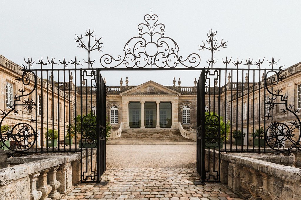 Elegant wrought iron gates and stone pillars at the entrance of a grand estate.